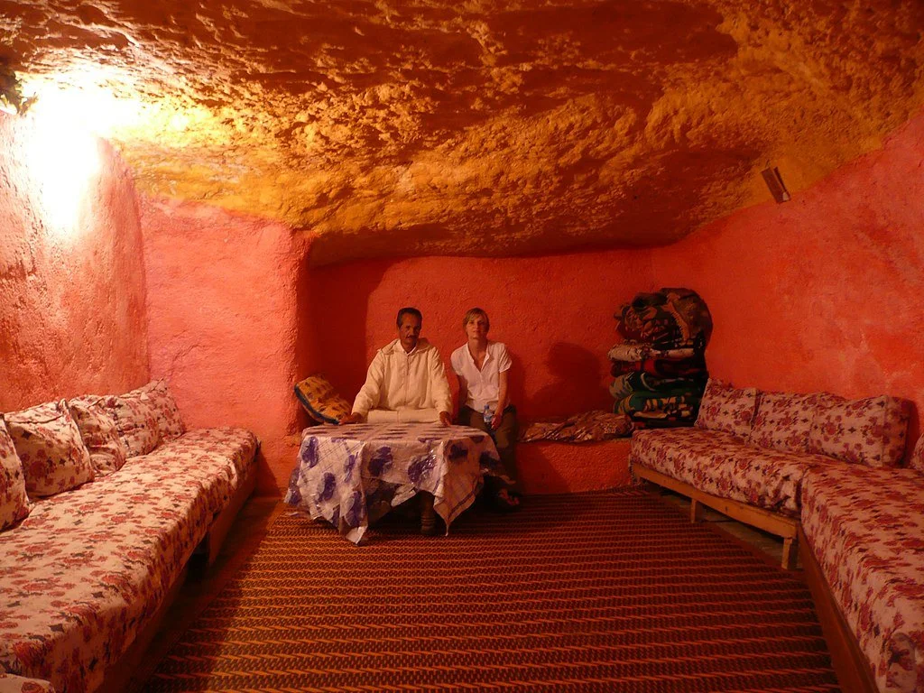 A man and woman sit inside one of the cave houses at Bhalil village in Morocco