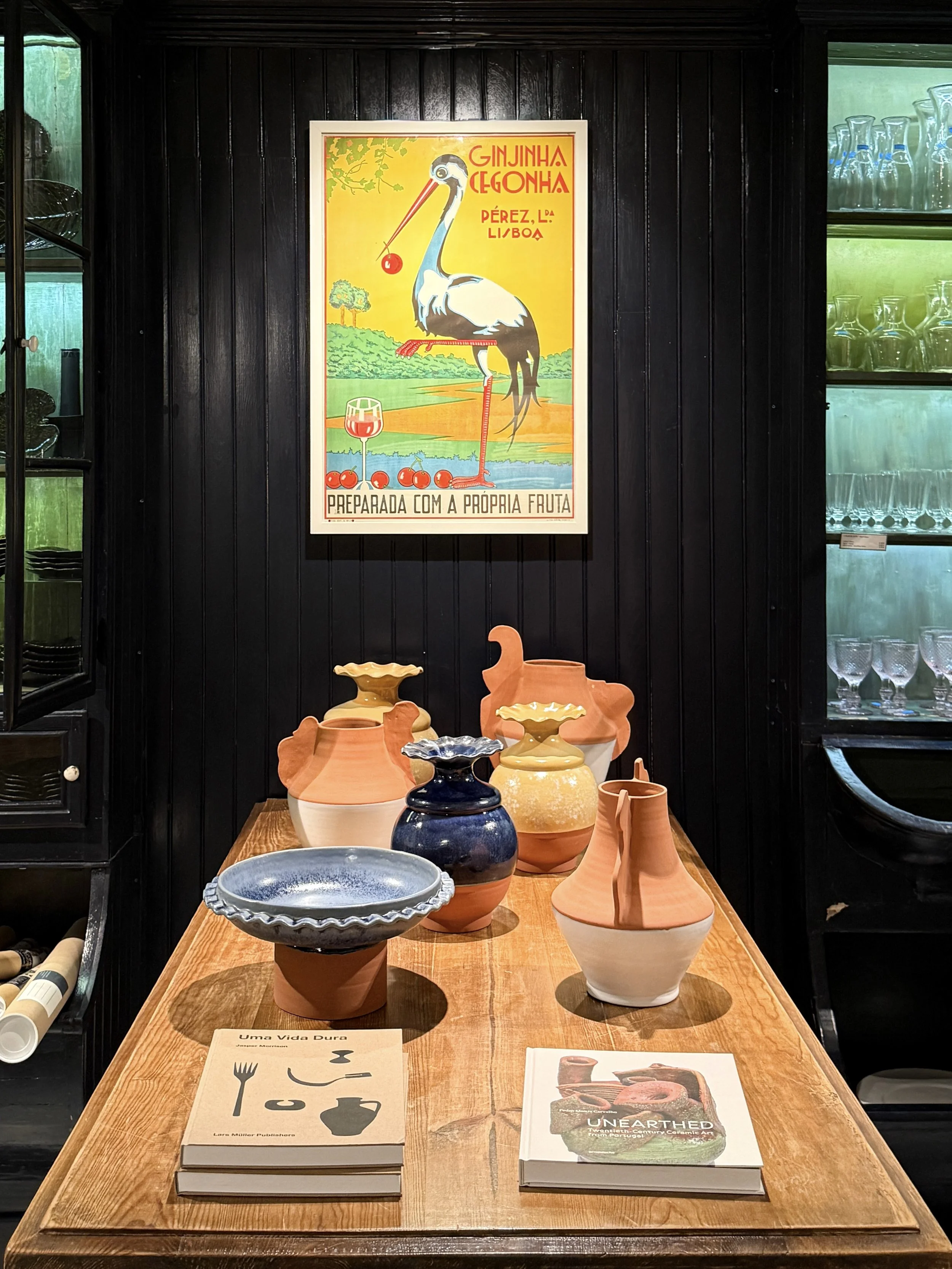 A wooden table displays terracotta and glazed pottery by Sam Baron x Maria, from the Porto de Mós region of Portugal