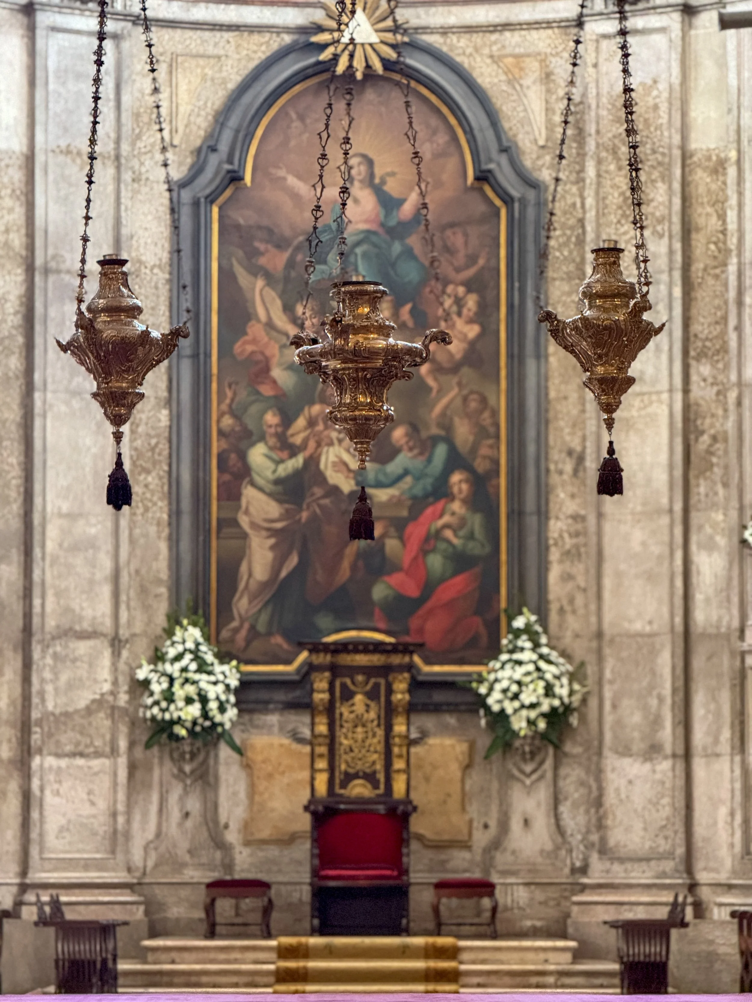 The Baroque 18th century painting above the high altar depicts the Assunção da Virgem (Assumption of the Virgin) and is attributed to José Inácio de Sampaio at the Lisbon Cathedral, with incense sifters hanging down