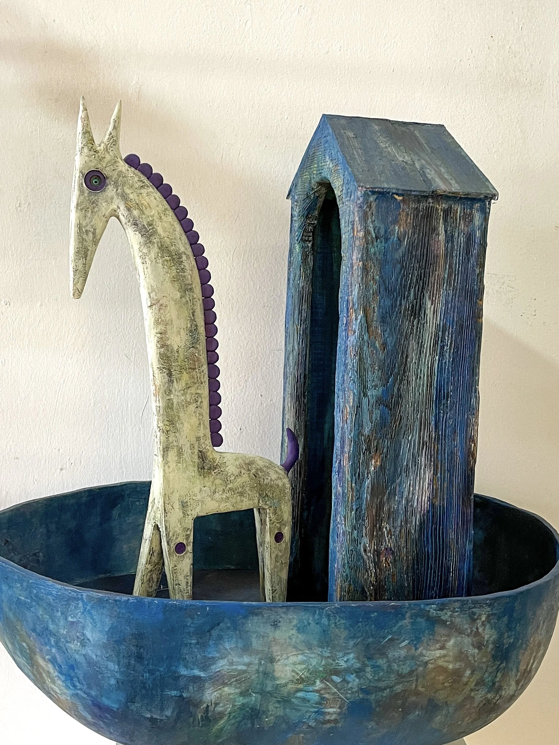 Small sculpture of toylike giraffe in a blue boat
