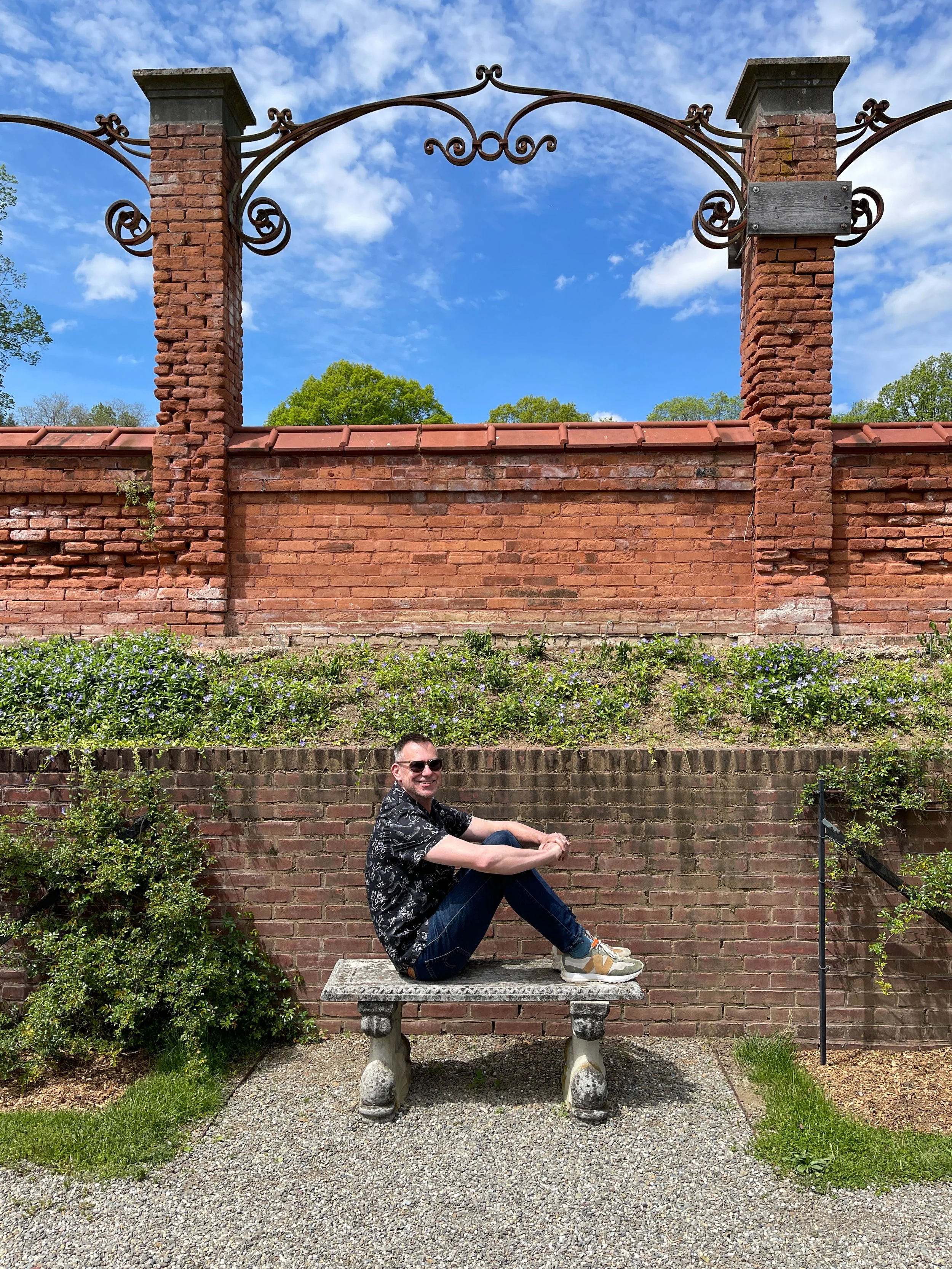Man sits on bench sideways in the garden at Vanderbilt Mansion