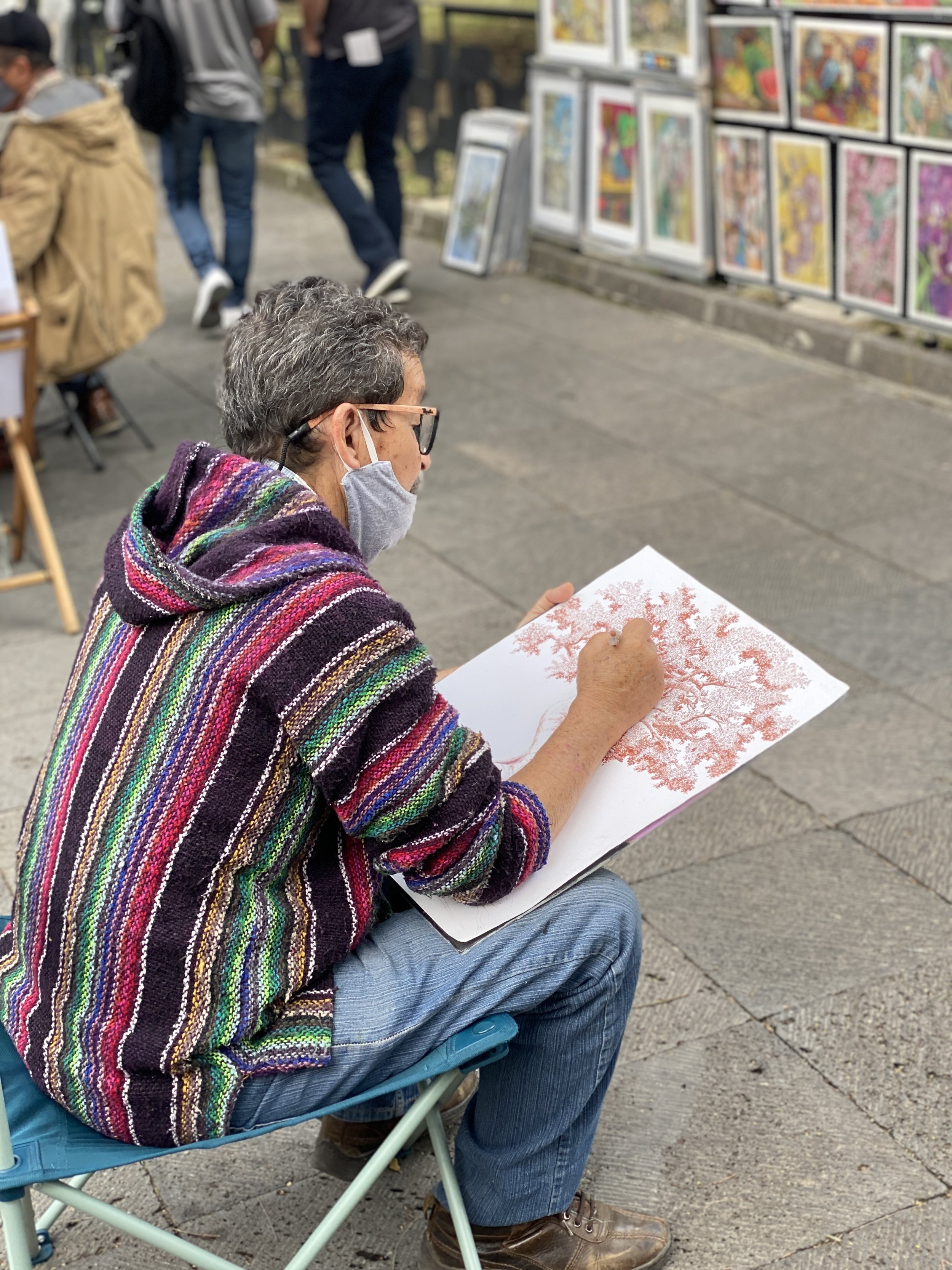 Artist working on a drawing outside at the Bazar Sábado