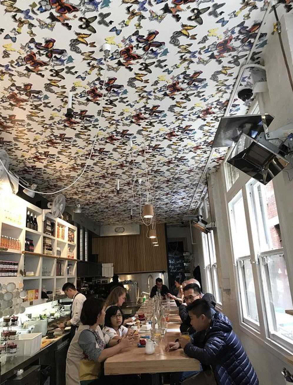 People sit at tables under a ceiling covered with butterfly stickers at Hardware Société in Melbourne, Australia