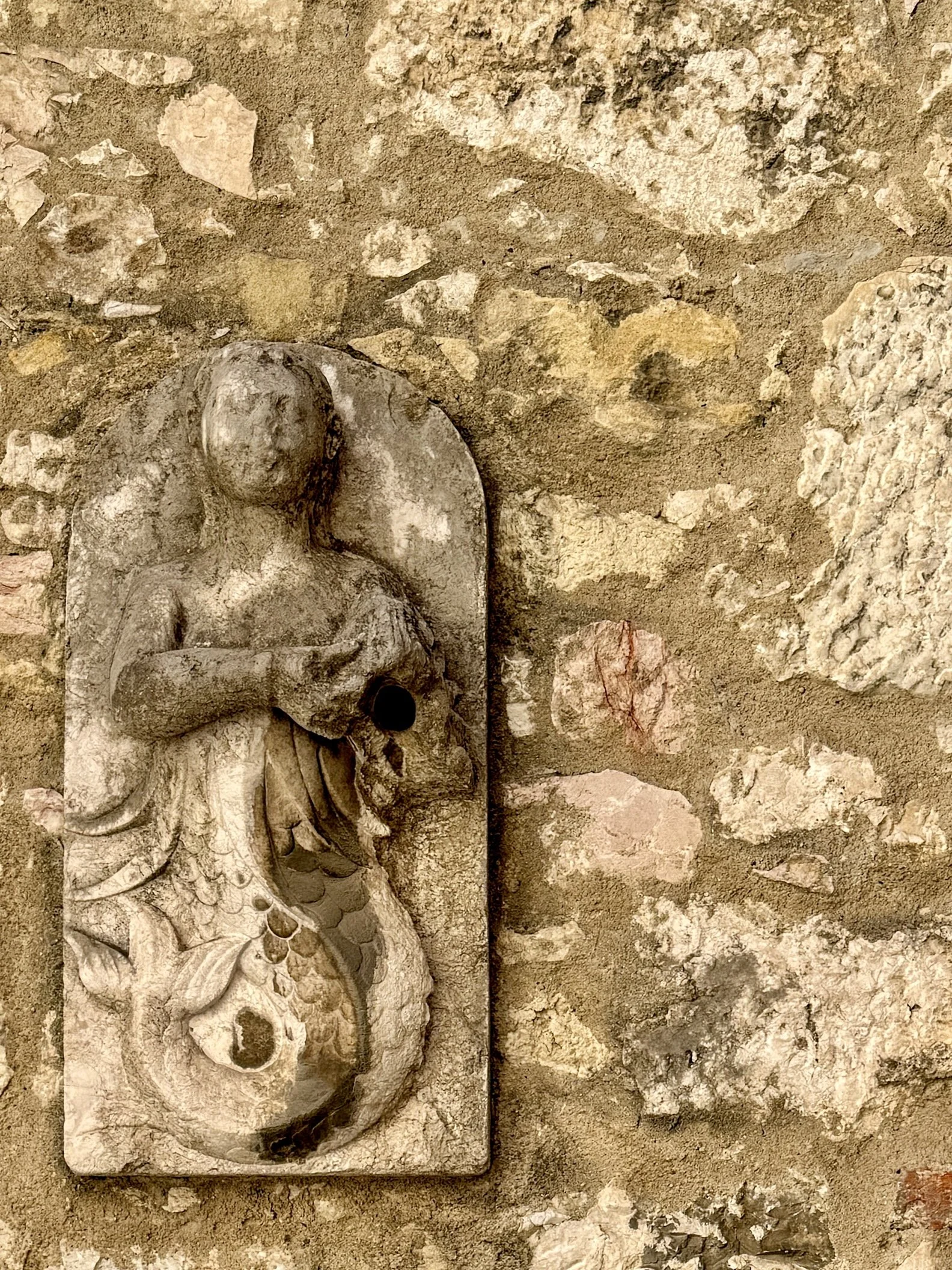 A limestone mermaid from the Monastery of São Dinis de Odivelas gazes from the wall of the Carmo Museum in Lisbon