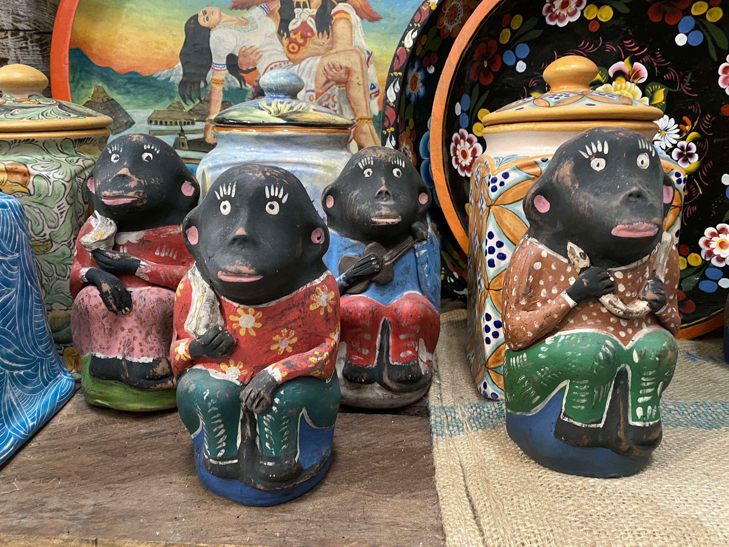 Row of changos mezcaleros, black clay vessels shaped like monkeys and painted in bright clothing