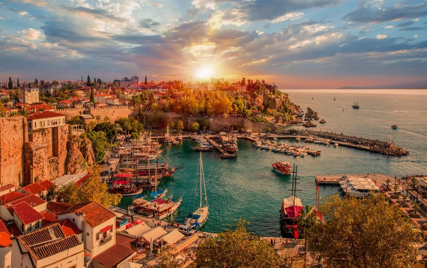 A harbor with sailboats and rocky hillsides in Antalya, Turkey at sunset
