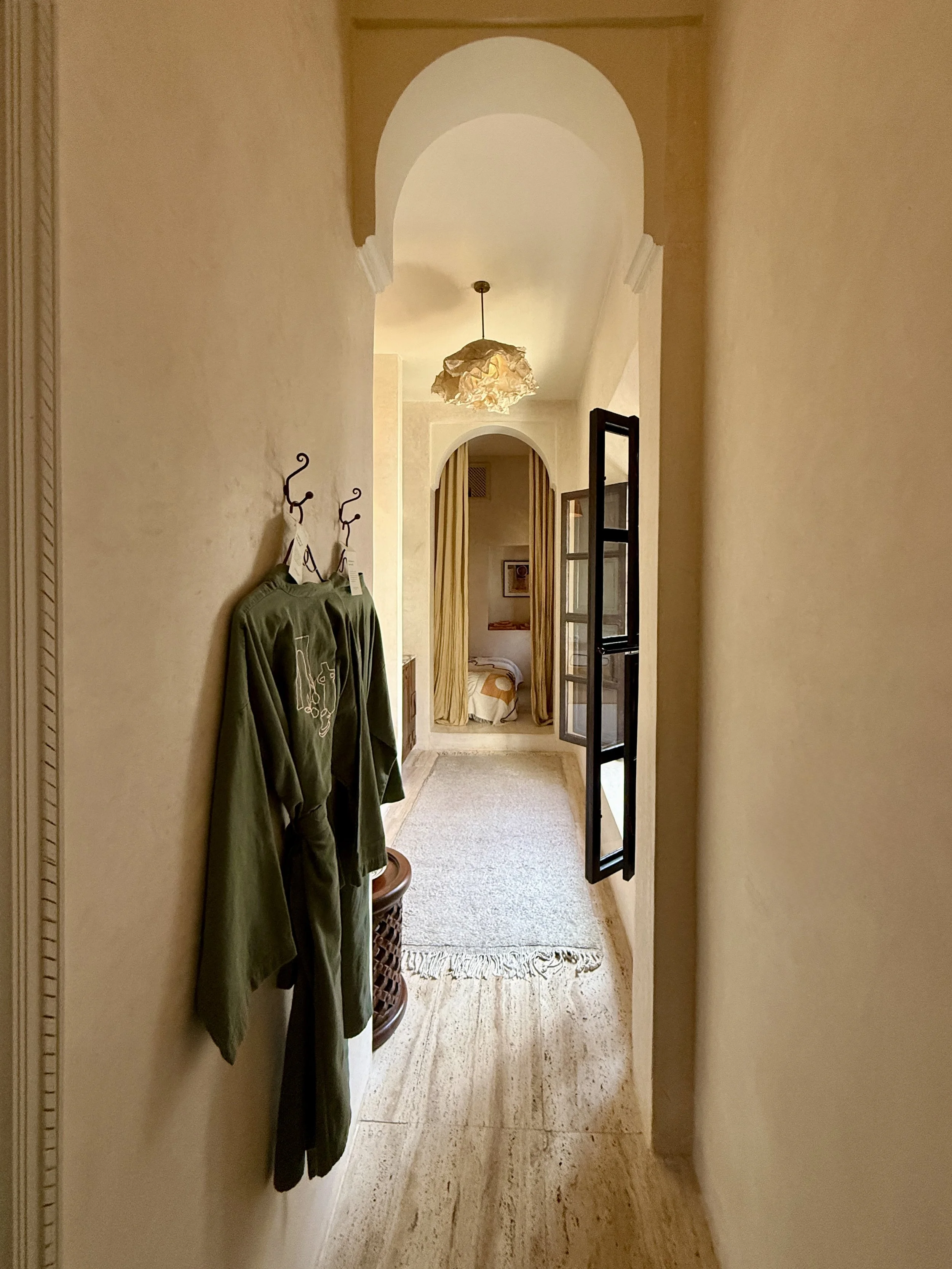 Robes hand on the wall in the narrow Cocoon room at Riad Rosemary in Marrkech