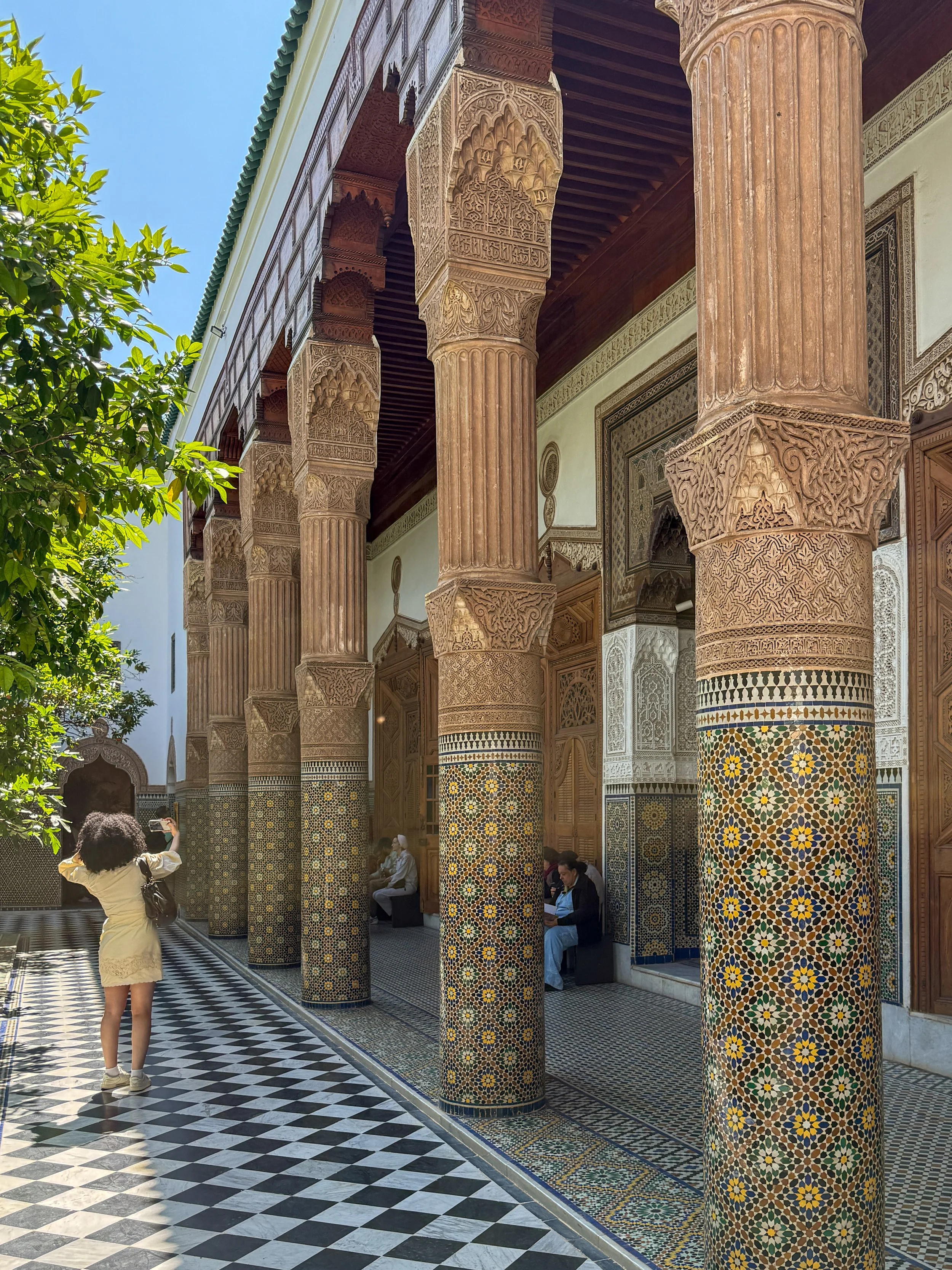 A woman takes a picture by tiled columns in the central courtyard at Dar el Bacha in Marrakech, Morocco