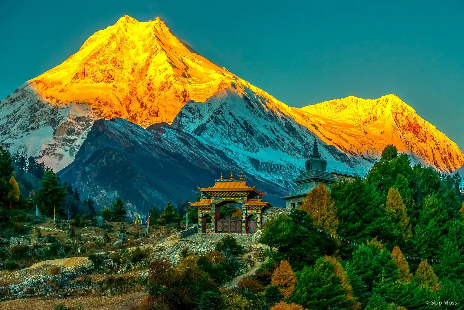 Sunset turns the mountains gold with a temple by a forest on the Manaslu Circuit trek in Nepal