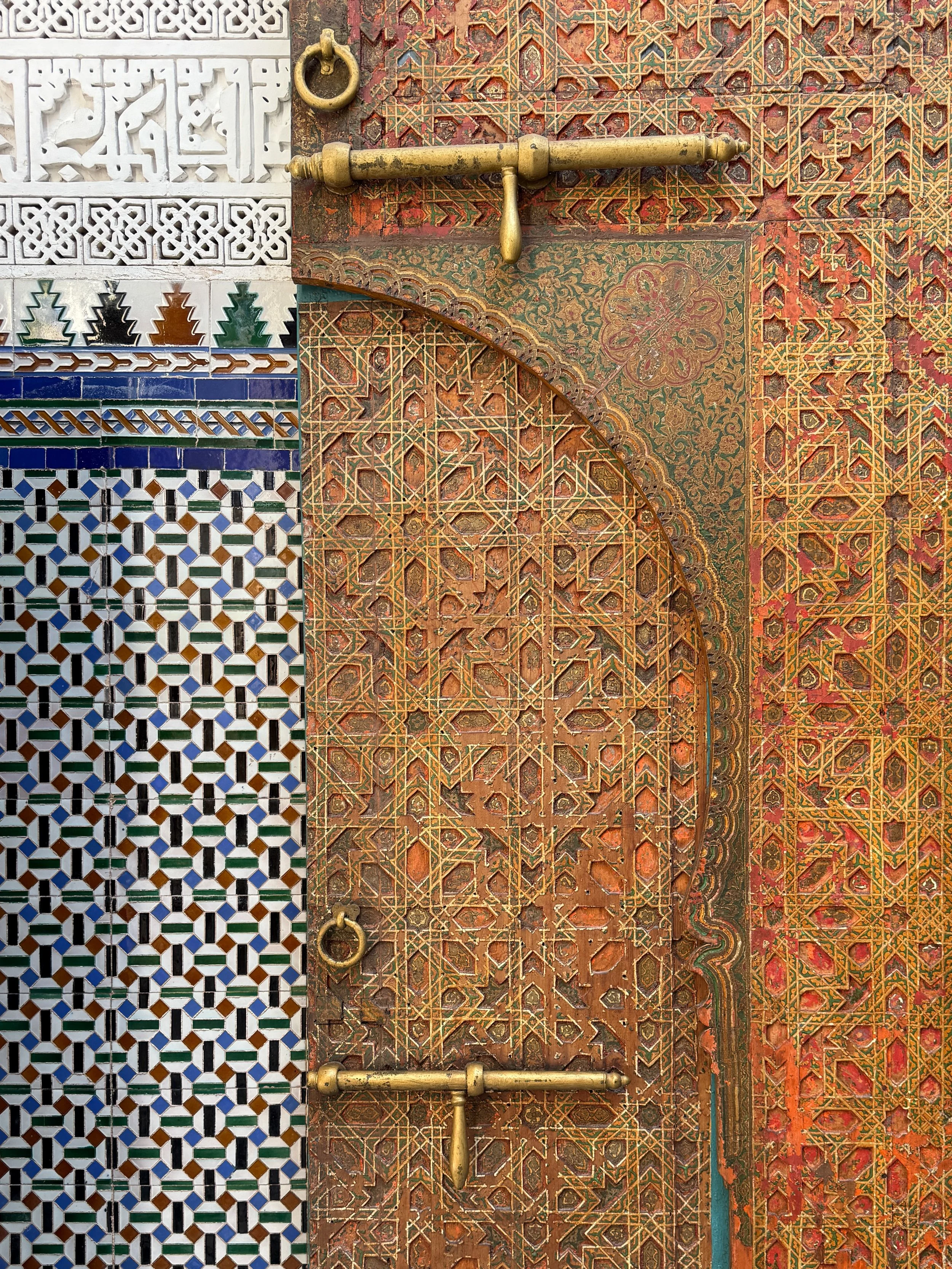 An ornately carved door by colorful tilework at Dar el Bacha in Marrakech