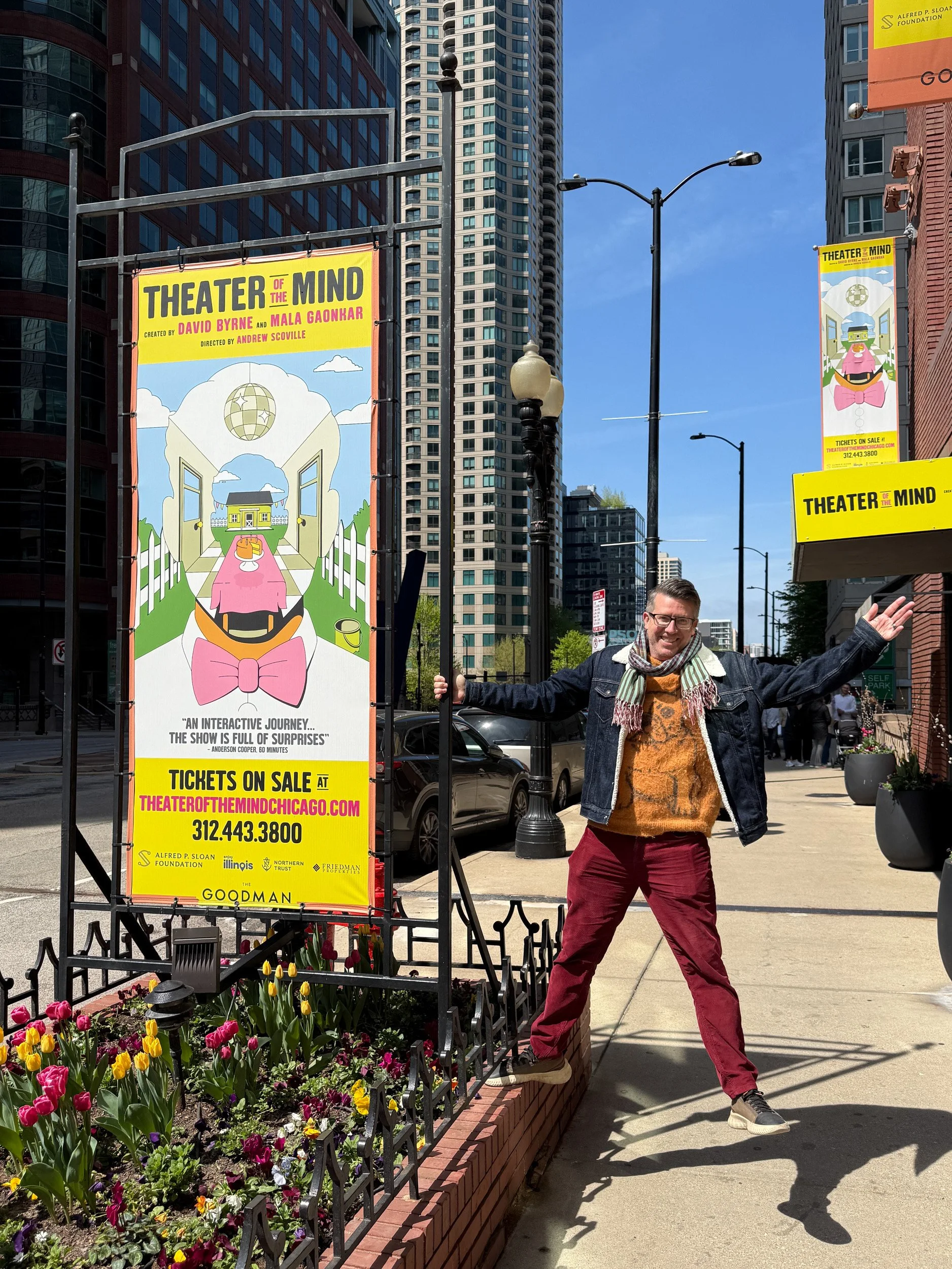 A man hangs off the sign for Theater of the Mind, an immersive experience by David Byrne, on a street in downtown Chicago