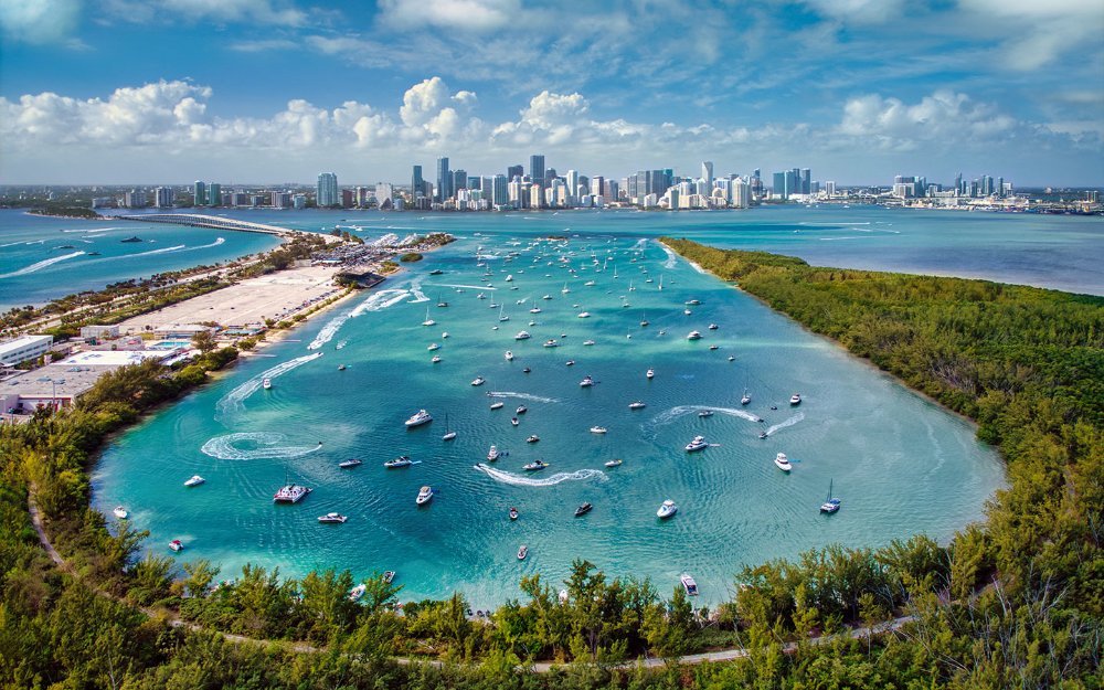 An aerial view of Key Biscayne, filled with motorboats, with Miami's skyline in the distance