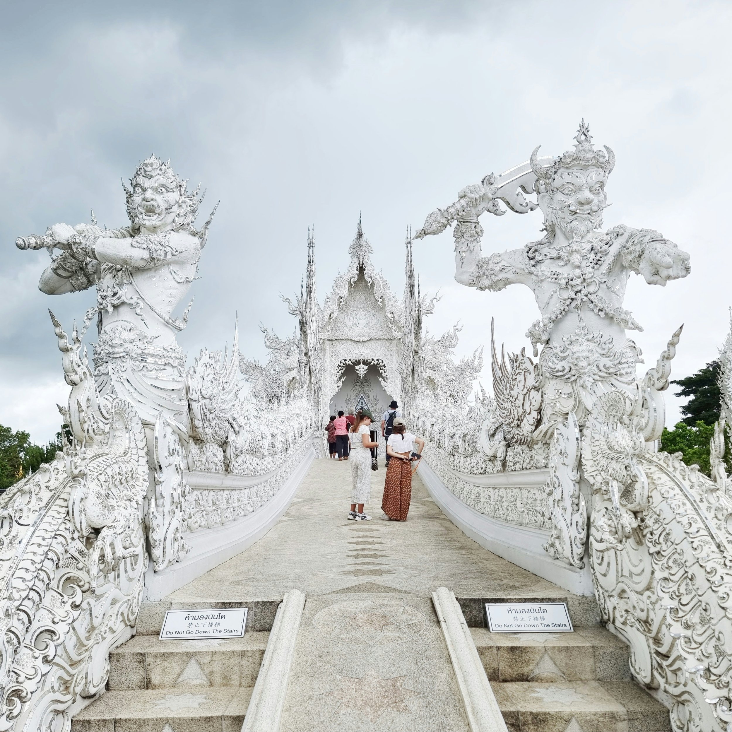 Fierce mythological figures holding weapons by the bridge to the White Temple in Chiang Rai, Thailand