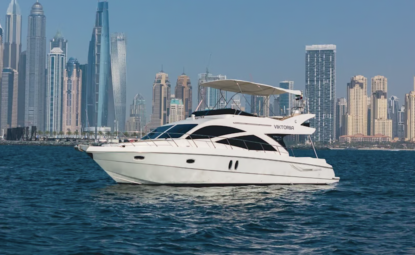 A yacht with the skyscrapers of Dubai behind it