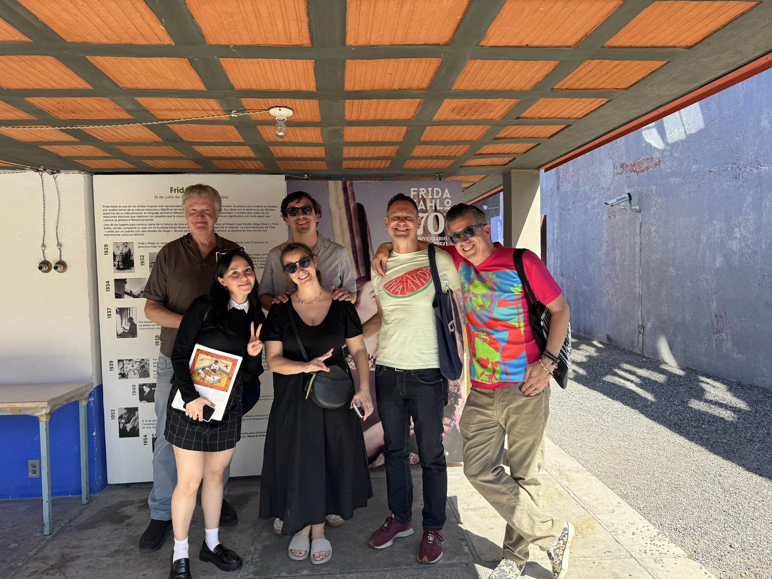 A tour group and their guide pose under the entrance to Frida's house at the Museo Casa Estudio Diego Rivera y Frida Kahlo