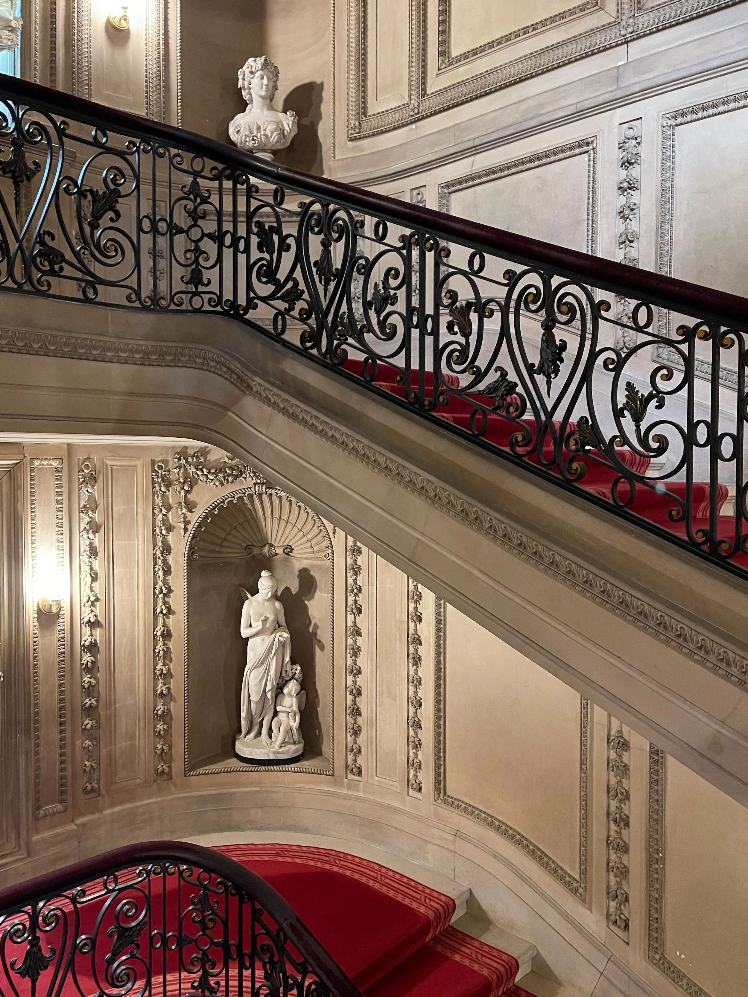 Statues in niches on landings of the staircase at Vanderbilt Mansion with ornate iron balustrade