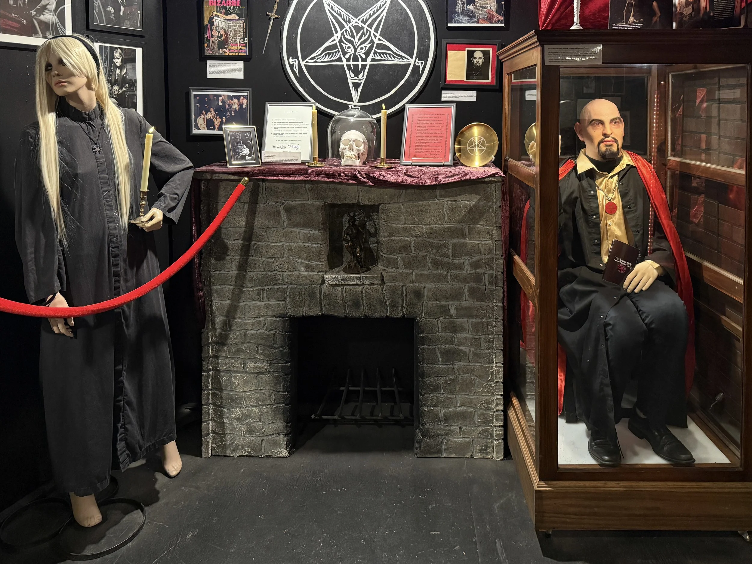 Two mannequins on either side of a fireplace, one of a blonde woman in black, the other of Anton LaVey, founder of the Church of Satan, at the Graveface Museum, Savannah