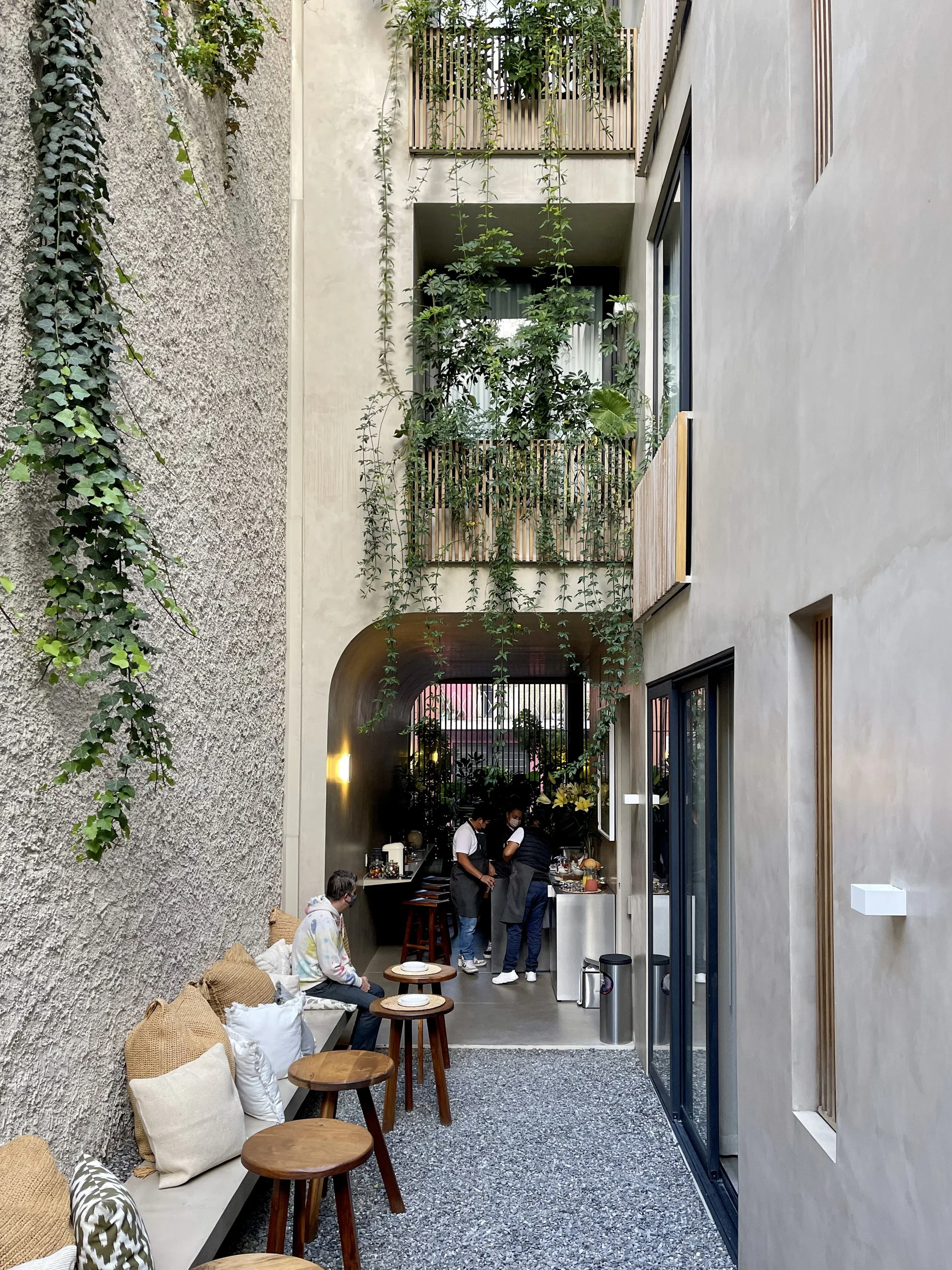 The interior courtyard / eating area with stones and plants trailing off balconies at Octavia Casa in Mexico City, Mexico
