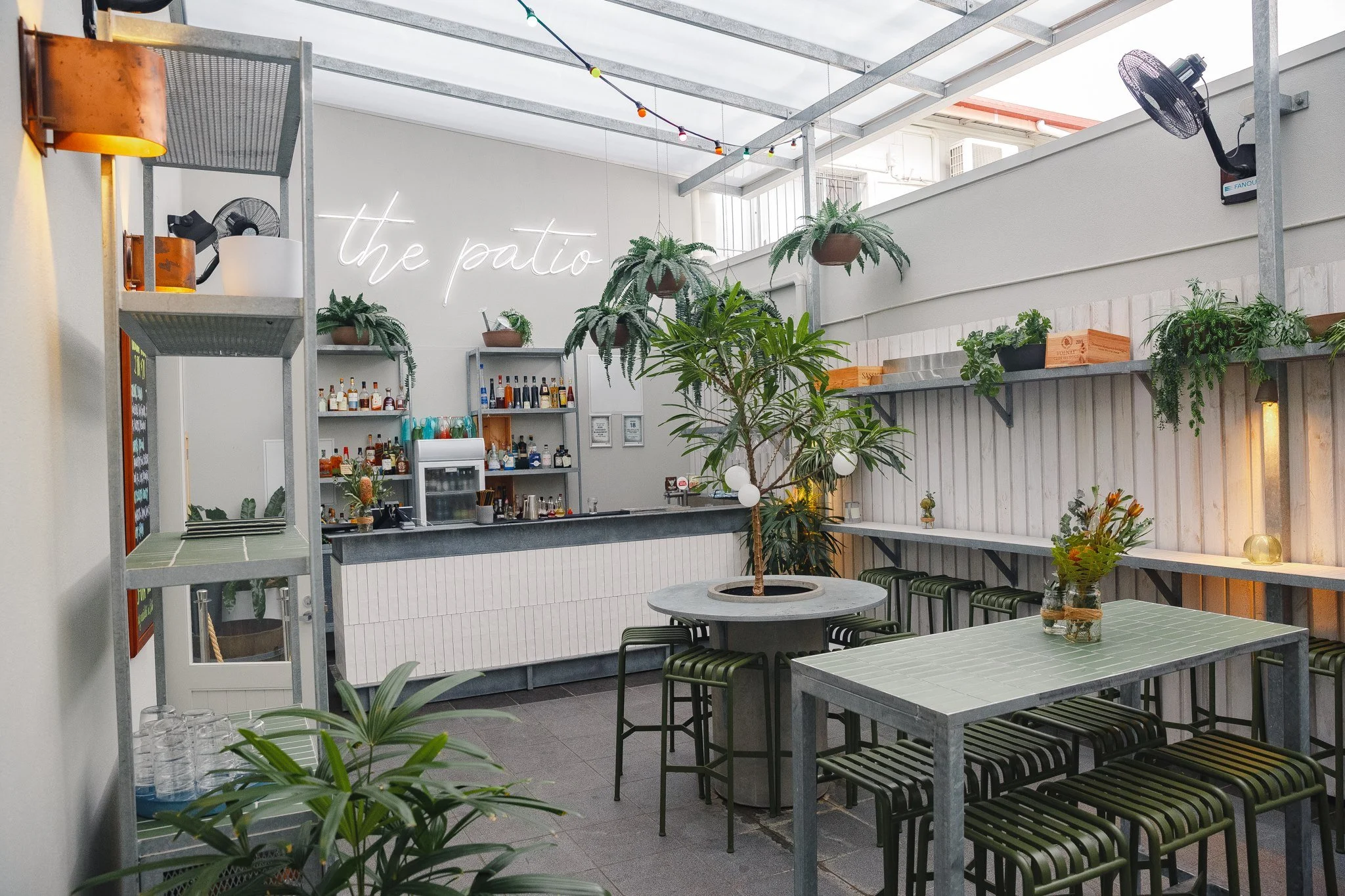 Gray tables, lots of plants and the back counter at the patio of The Chambers restaurant in Cairns