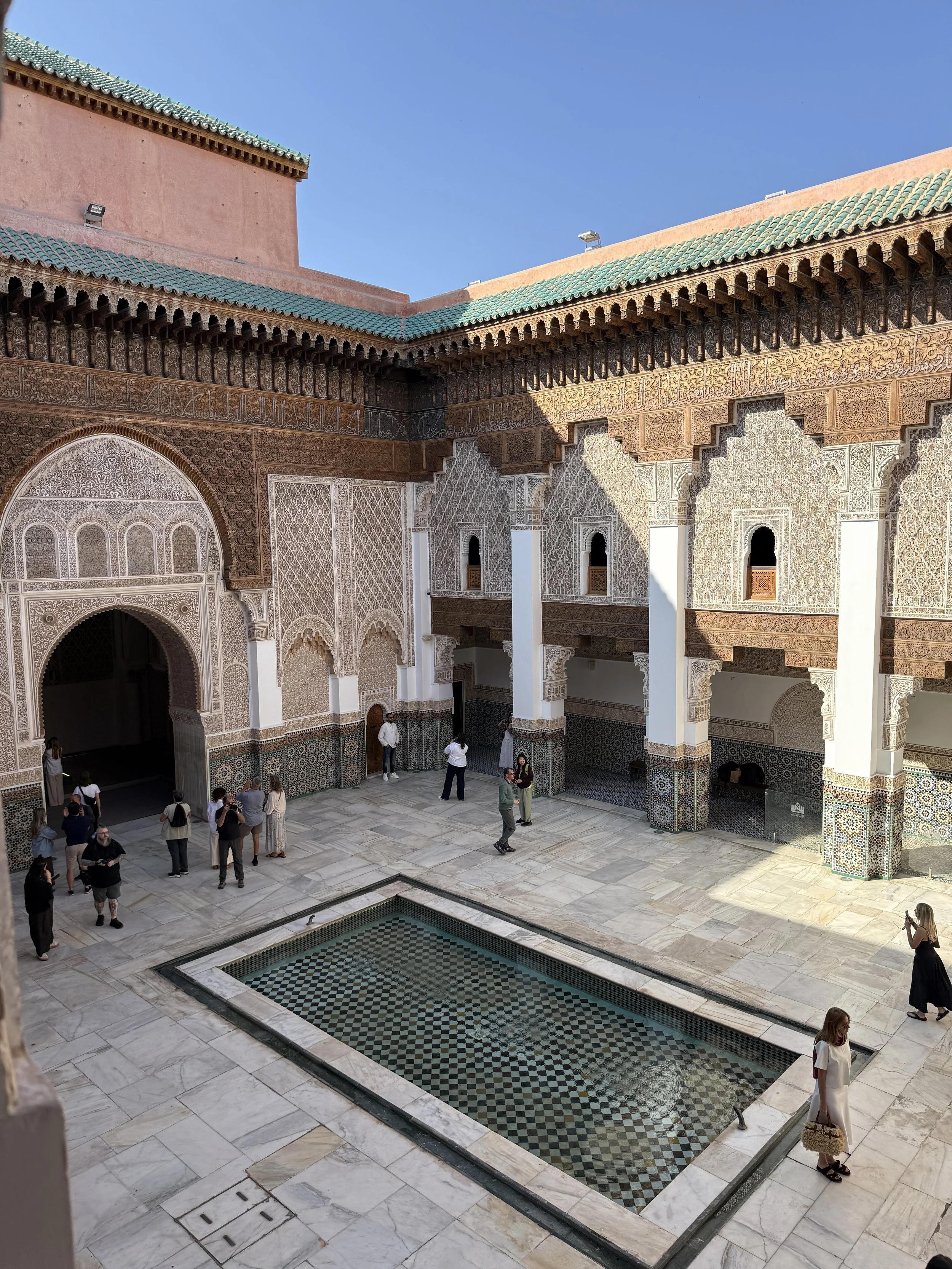 Tourists visit and take photos in the courtyard of Ben Youssef Madrasa in Marrakech