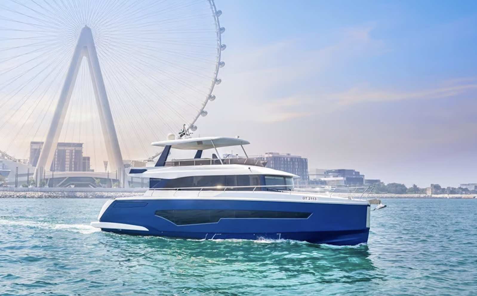A blue and white yacht off of the giant Ferris wheel in Dubai