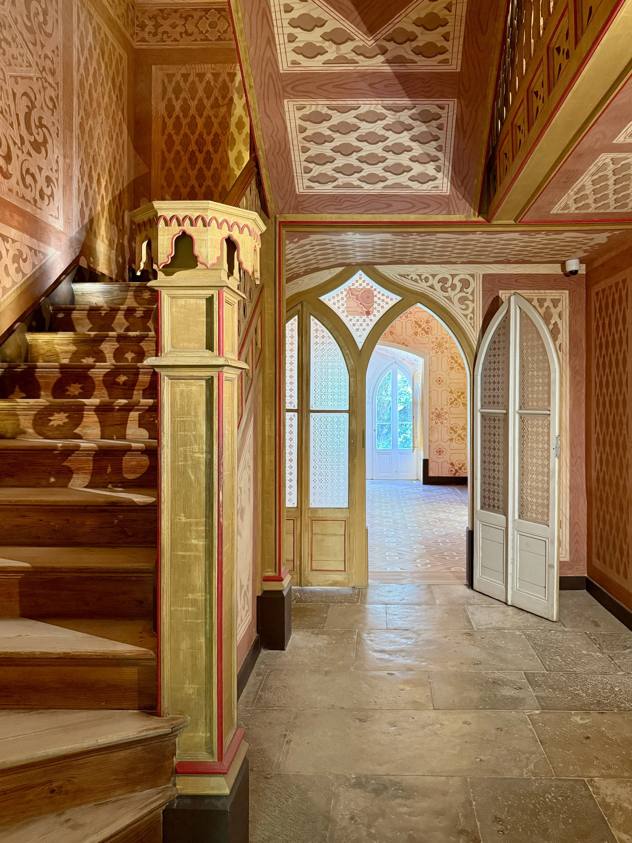 The foyer of the  Chalet da Condessa d’Edla in Sintra, with staircase, wood-paneled walls and ceiling and artched doorway