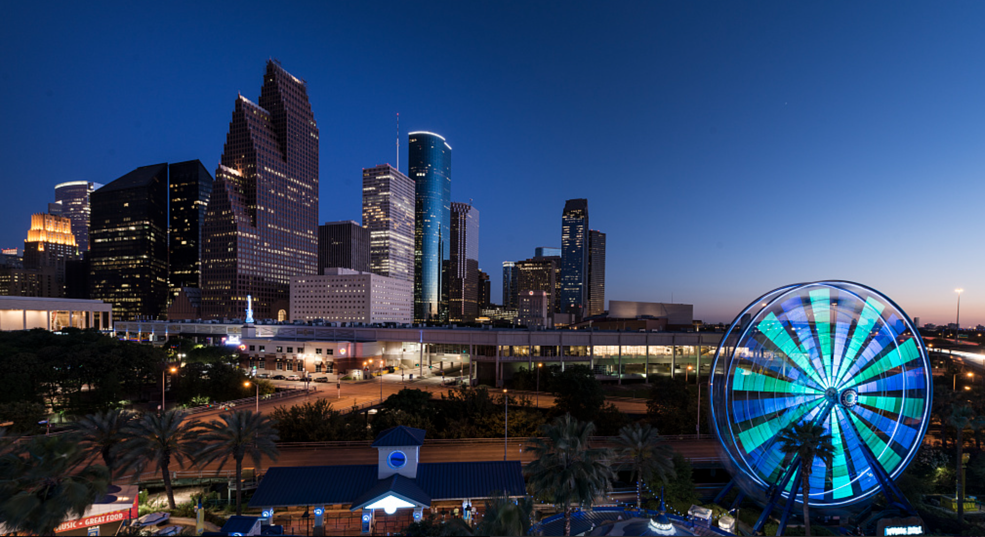 The Houston, Texas skyline at night, with a lit-up Ferris wheel in the foreground