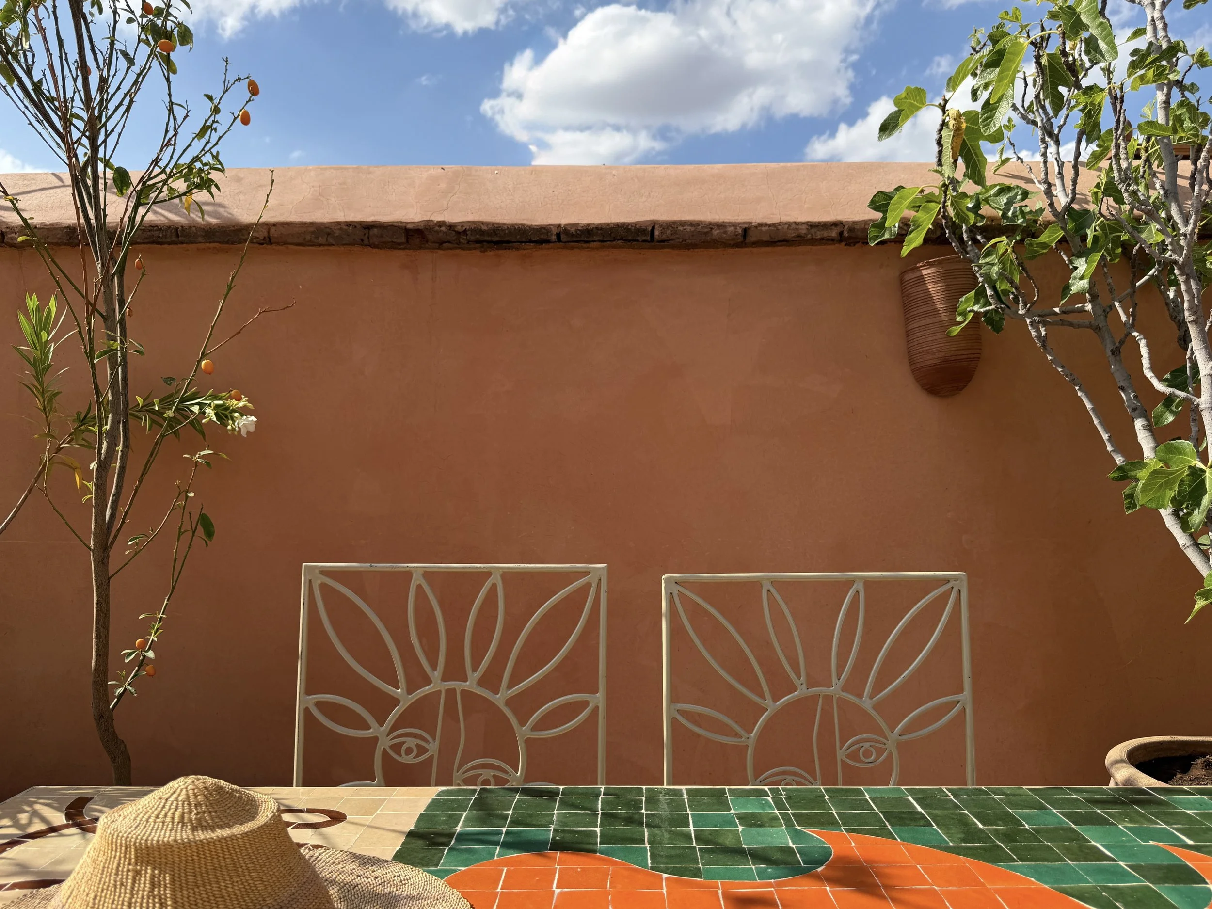 Mosaic table and wire chairs with suns on the rooftop terrace at Riad Rosemary in Marrakech, Morocco