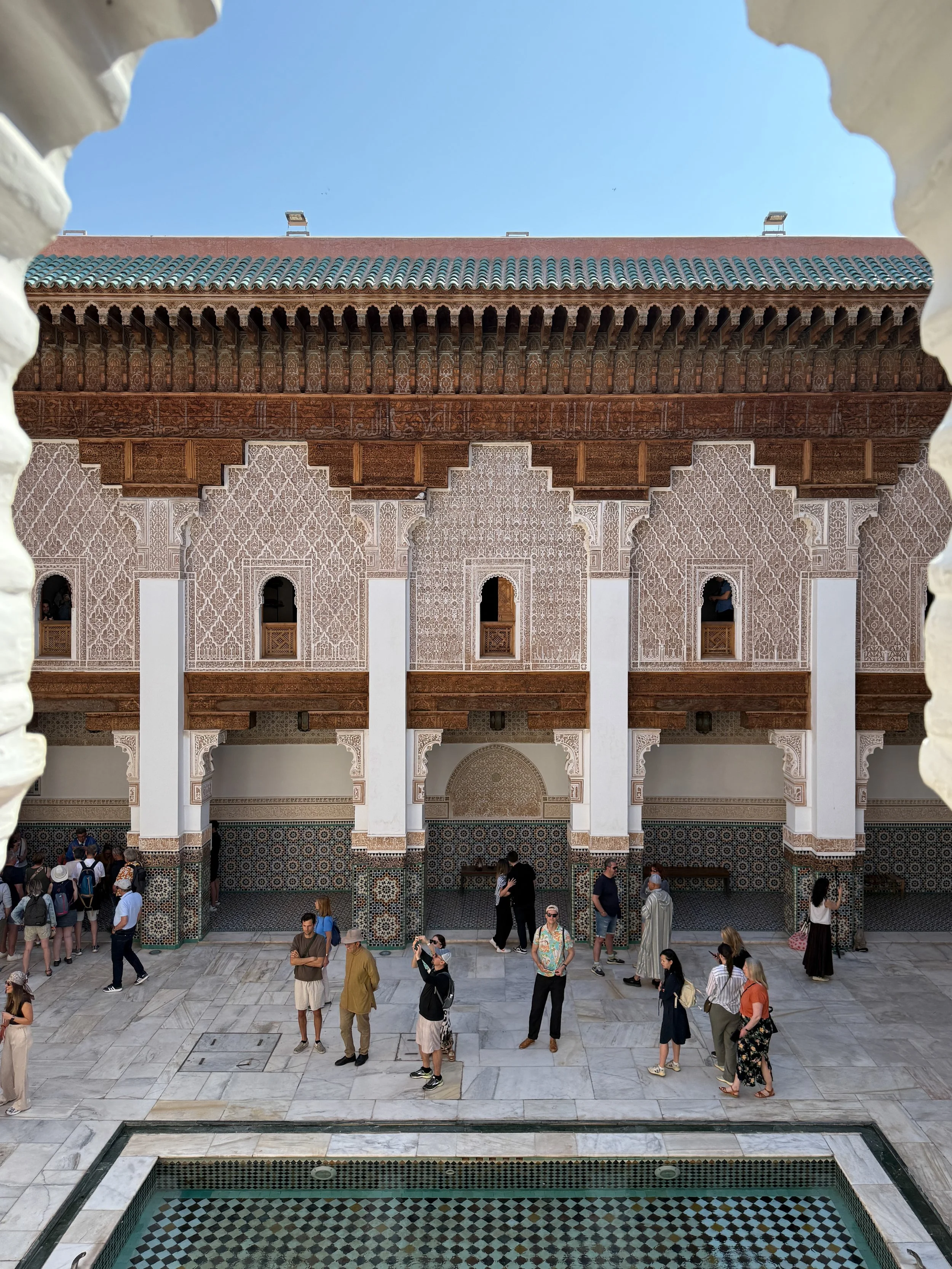 Tourists mill about the courtyard of Ben Youssef Madrasa in Marrakech