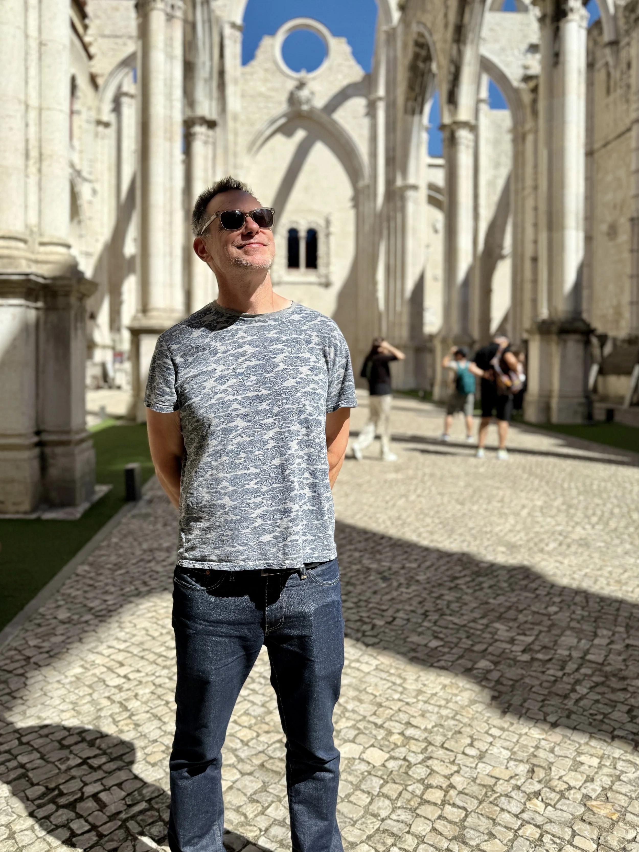 A man stands in the ruins of the Carmo Convent, now the Carmo Archaeological Museum