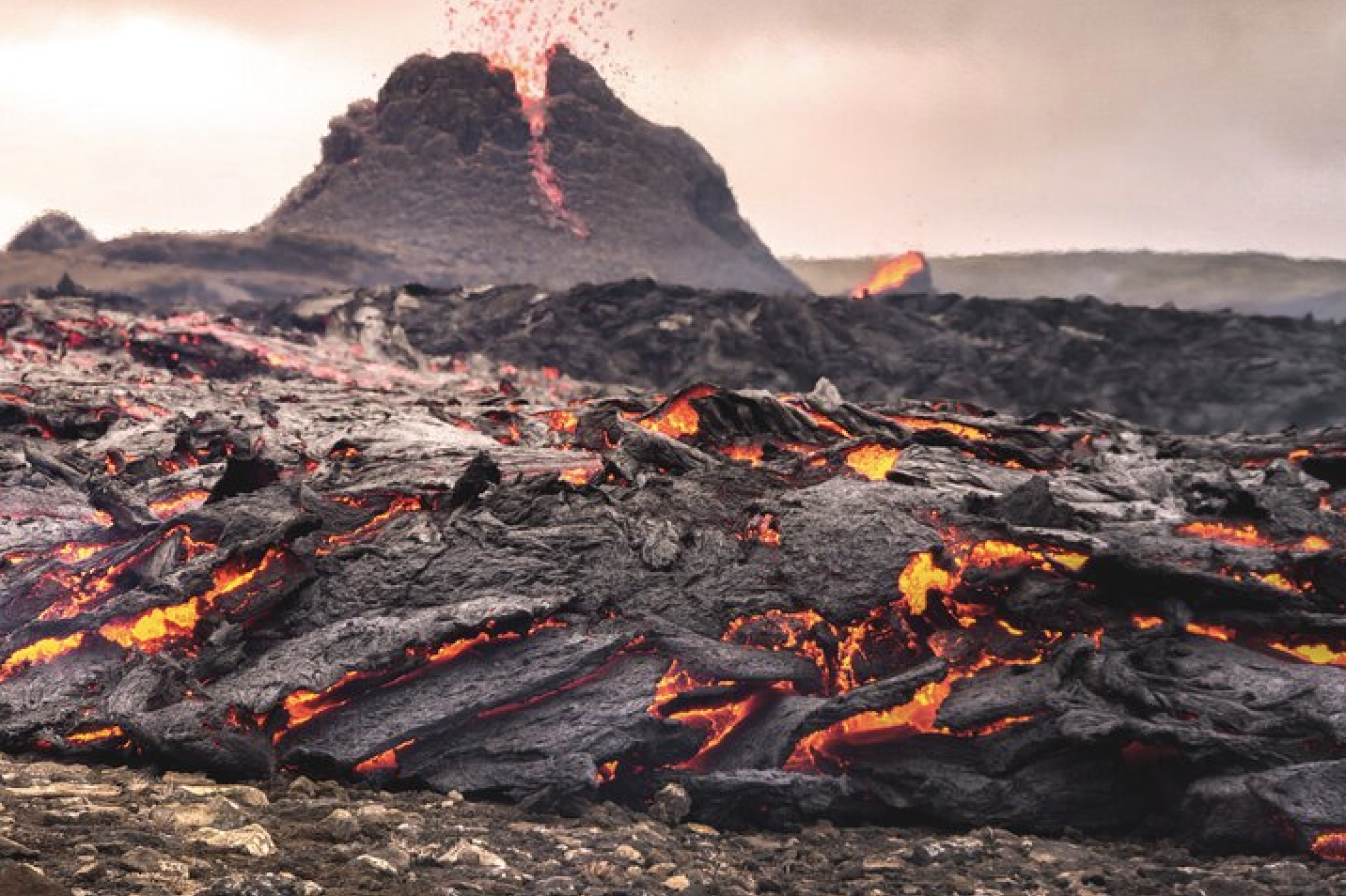 The volcano Fagradalsfjall in Iceland erupts, with black volcanic rock, lit by orange magma