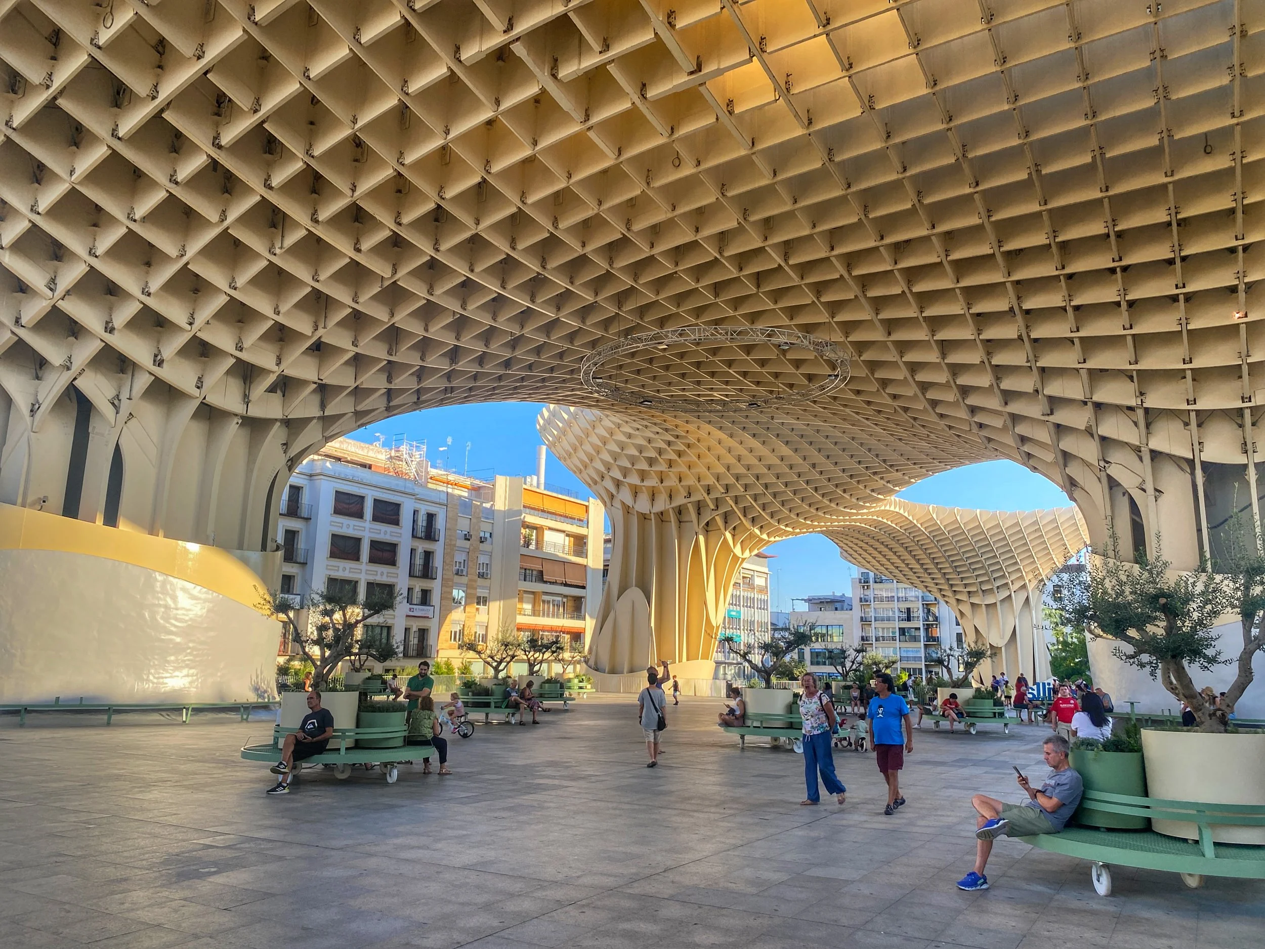 People walk and sit on benches under Las Setas in Seville