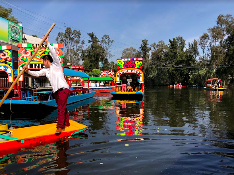 A man paddles one of the flat-bottomed boats that cruise the canals of Xochimilco outside of CDMX