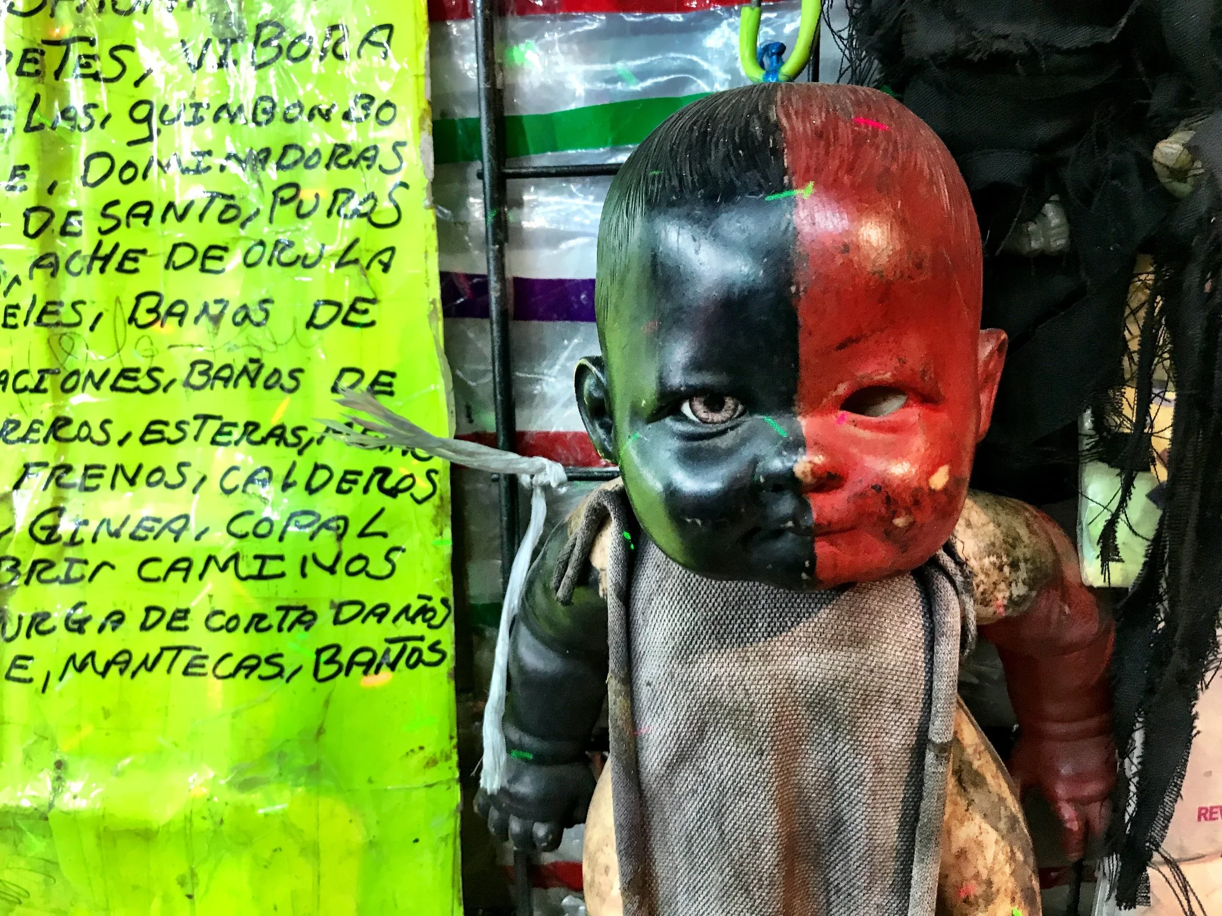 A doll painted half black, half red as the Santeria deity Lucero at the Sonora witch market in CDMX