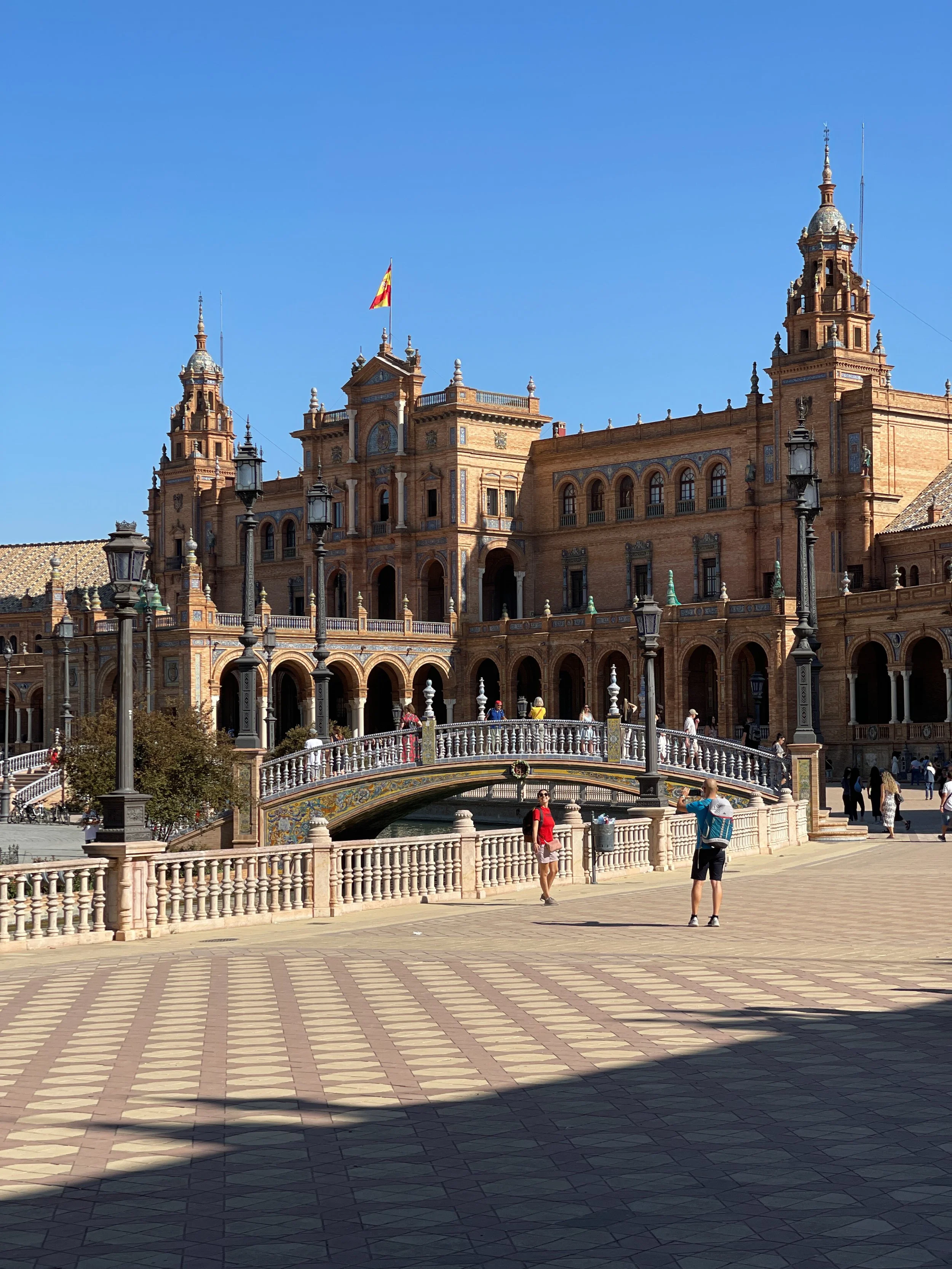 Building and bridge in the Plaza de España, where a tourist poses for a photo