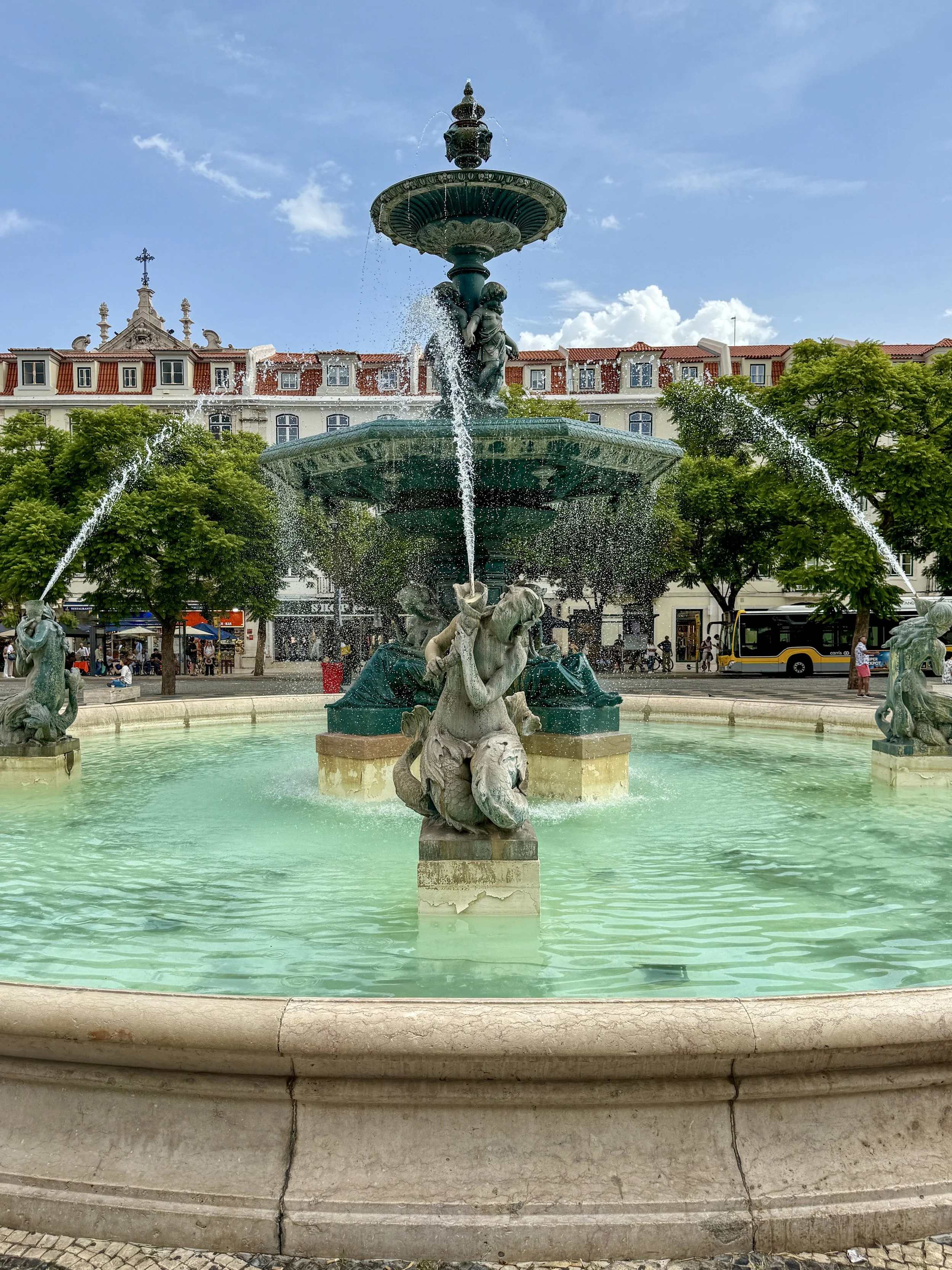 One of the Rossio fountains, featuring bronze mermaids and other sea creatures, spouting arcs of water