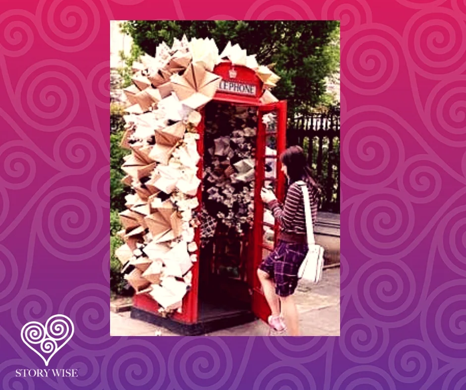  Woman about to enter a red phone booth covered in origami 