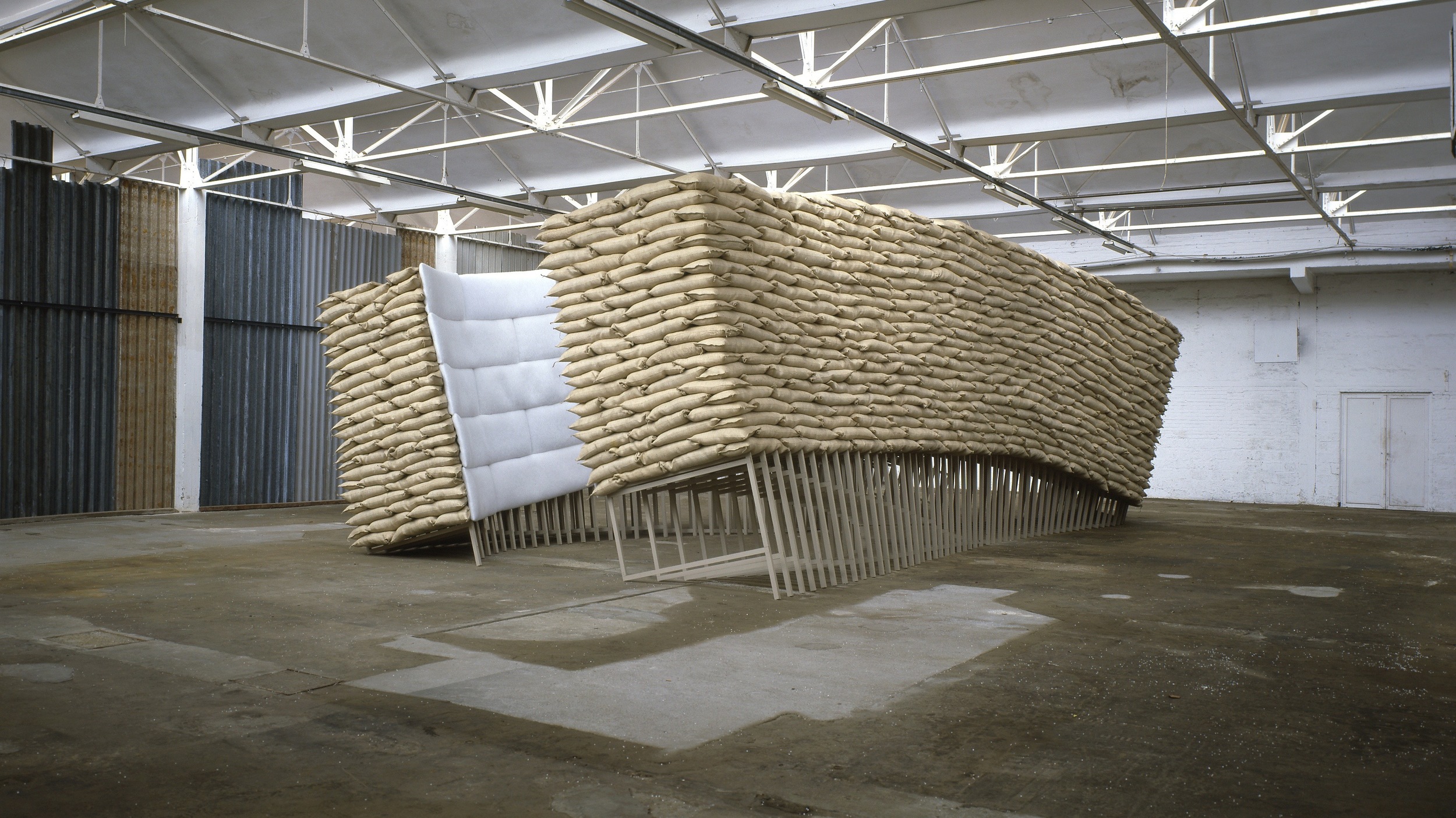   Nancy Turlington, 1994 , wood, sandbags, putty, upholstery, 372 x 604 x 1221 cm. Installation view at Kanaal, Kortrijk, Belgium 