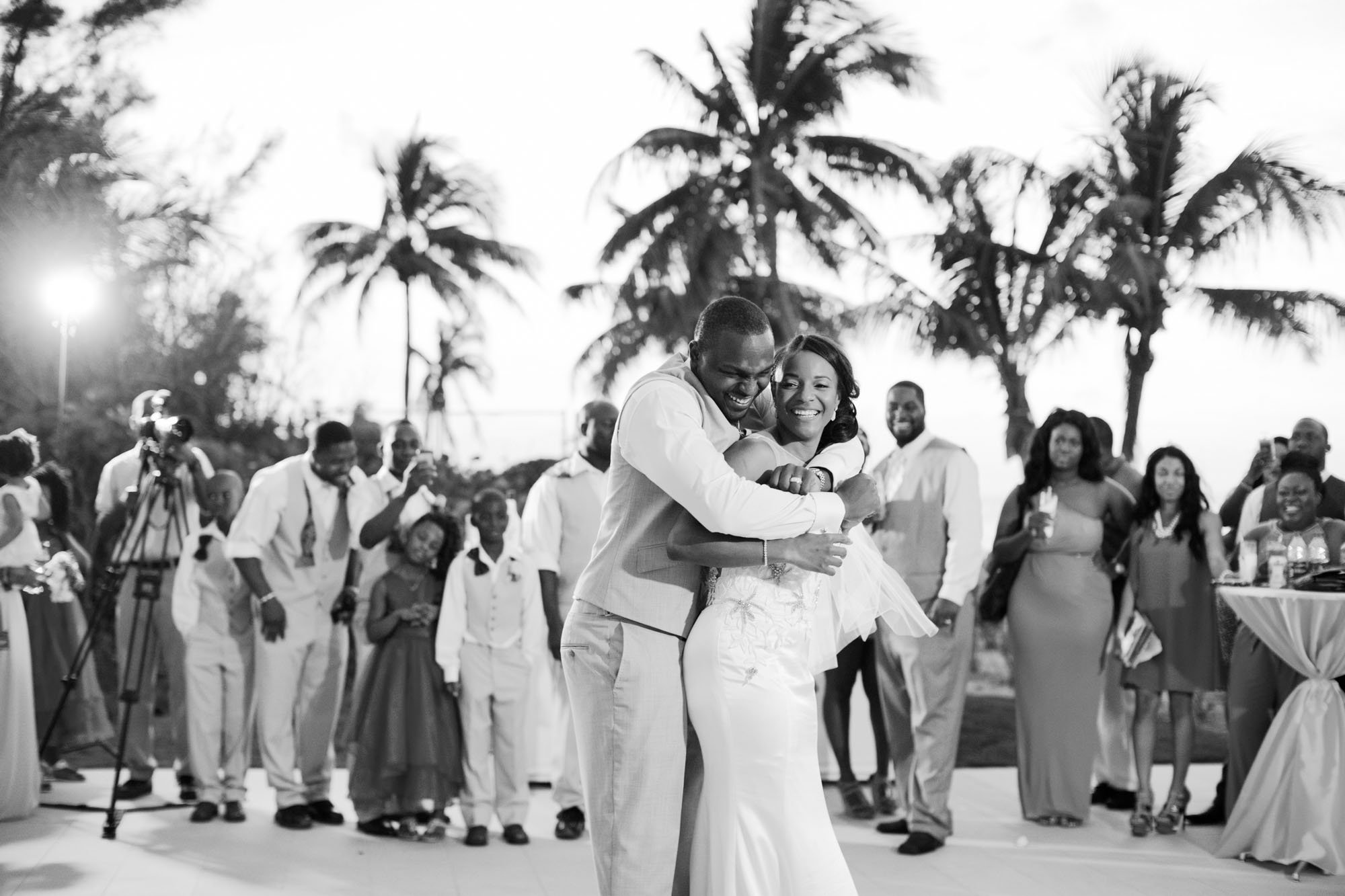 Black and white first dance of Super Bowl MVP Cliff Avril and Dantia, surrounded by guests and palm trees at their Bahamas destination wedding.