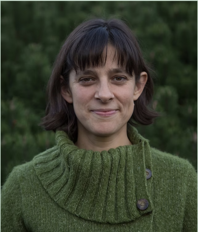 Image of Sarah Carl, a white woman with brown eyes and brown hair, wearing a green sweater
