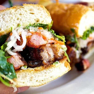 GRILLED PORK BELLY , baguette, Asian slaw, chilli jam dressing &amp; spicy mayo   from  $9,-