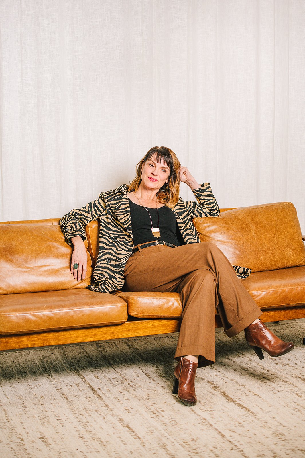 woman seated on brown leather sofa casual portrait session beauty personal branding