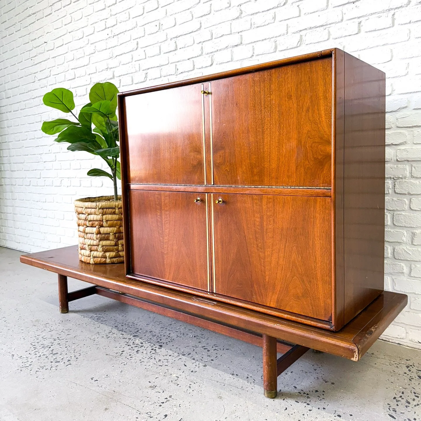 Here’s a pretty unique piece: it’s a 1960s walnut bar cabinet that sits on a nice, sturdy walnut bench. The cabinet can be placed anywhere on the bench to fit your room/style. 
The cabinet features a drop down bar light lights up from be
