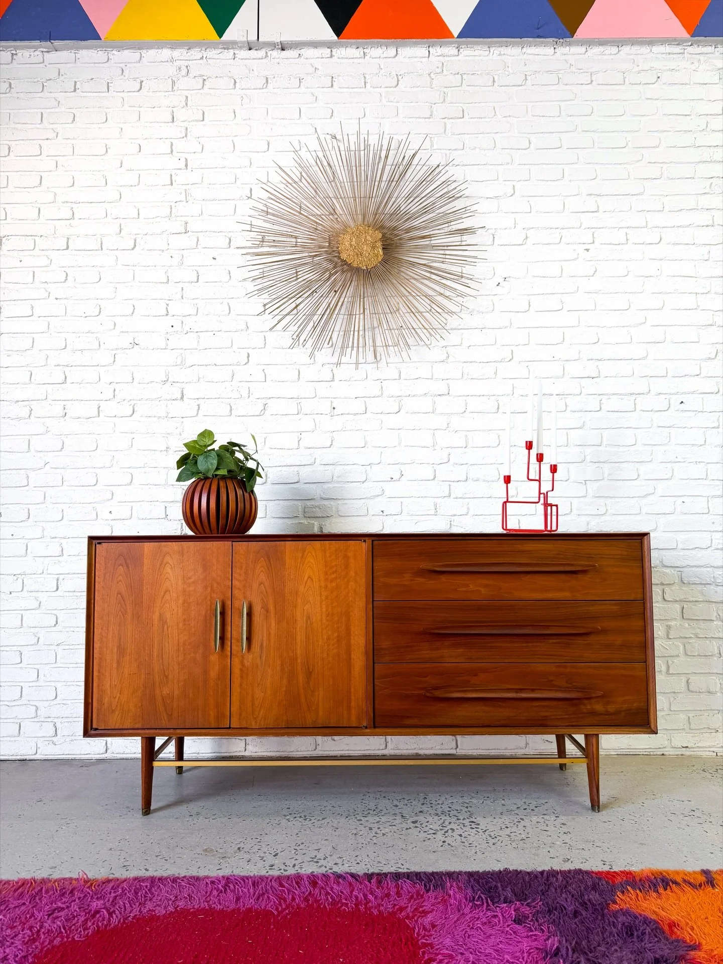 Well made American mid century modern credenza from the 1960s. Long, solid wood sculptural drawer pulls on three large drawers, and a large open storage area on the left side. 

Good original condition, with some shadowing on top where a hutch top us