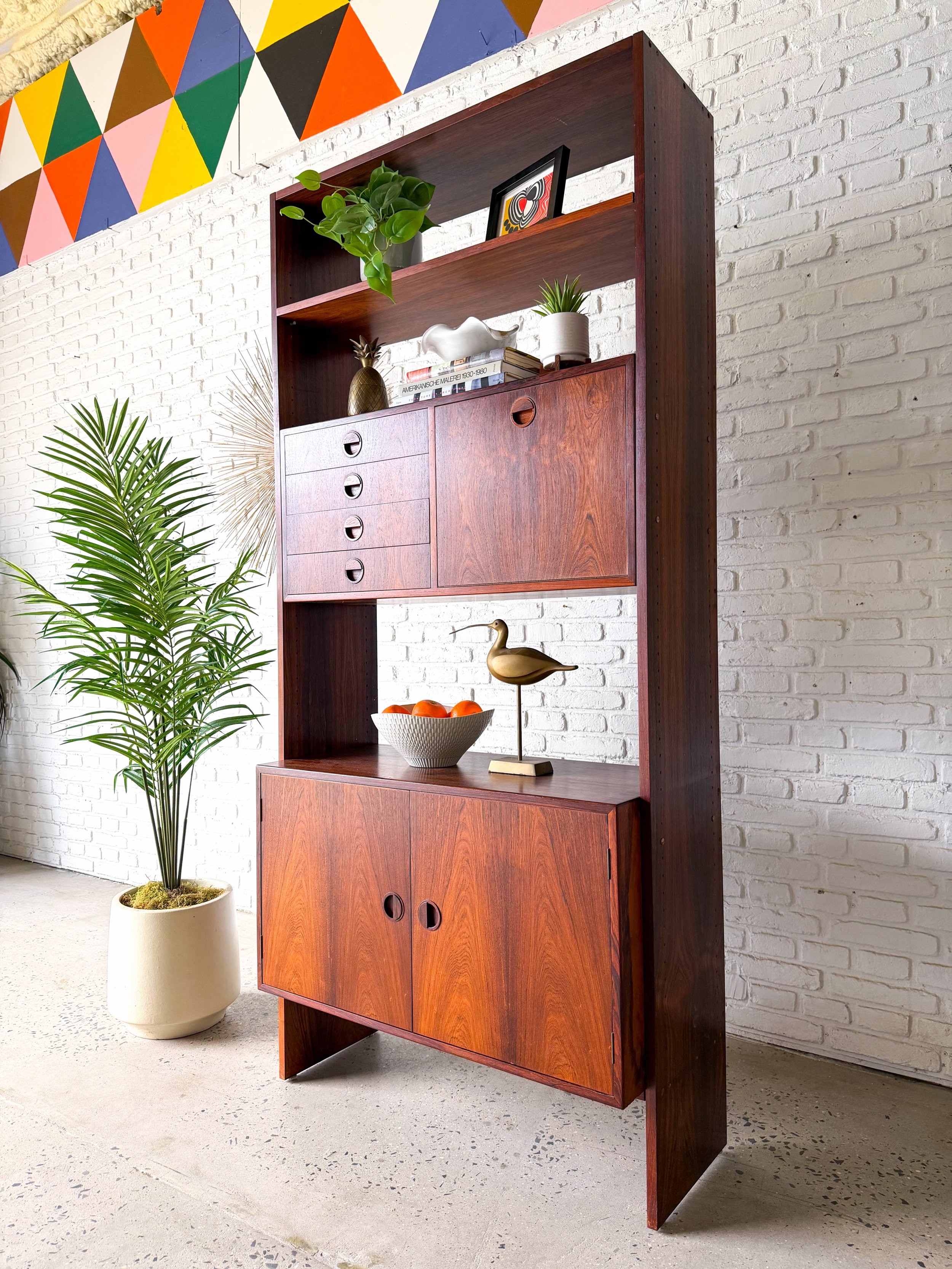 Freestanding Danish modern rosewood shelving unit. Features a drop-down bar surface, little drawers, open shelving, and plenty of hidden storage in the bottom cabinet.

Beautiful piece with such character.

37&rdquo; w x 16&rdquo; d x 80.25&rdquo; ta