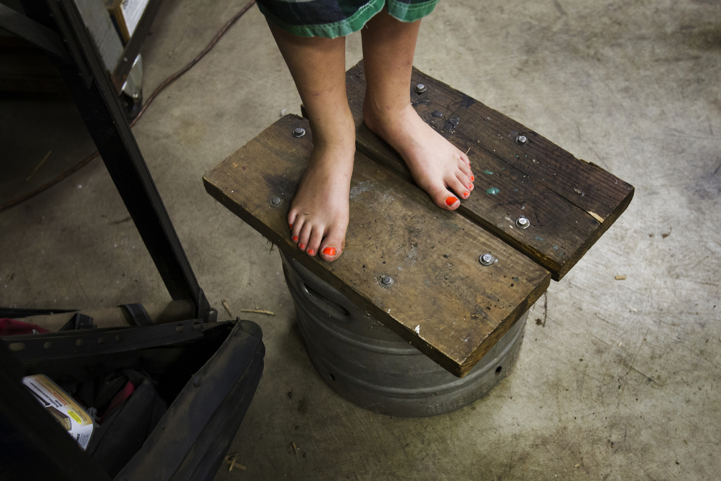  Sydnie Abke, 10, stands barefoot on a bucket in the garage where her father, Russ, stores the family's farm equipment on their property near Pemberville, Ohio.  