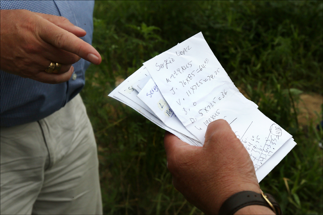  Handwritten payment slips, delivered to migrant workers, are inspected during a tour of migrant laborer camps organized by the Farm Labor Organizing Committee outside Raleigh, N.C., on July 28, 2014. British Members of Parliament Ian Lavery and Jame