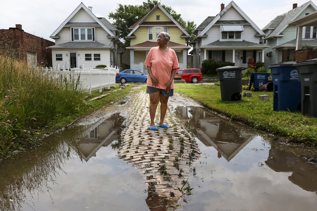  Norma Jean Williams, 72, stands near a flooded area of Norwood Court, an old brick road located just outside downtown Toledo. Ms. Williams has lived at a home located on Norwood Court since 1991 and has watched it crumble into severe disrepair. The 