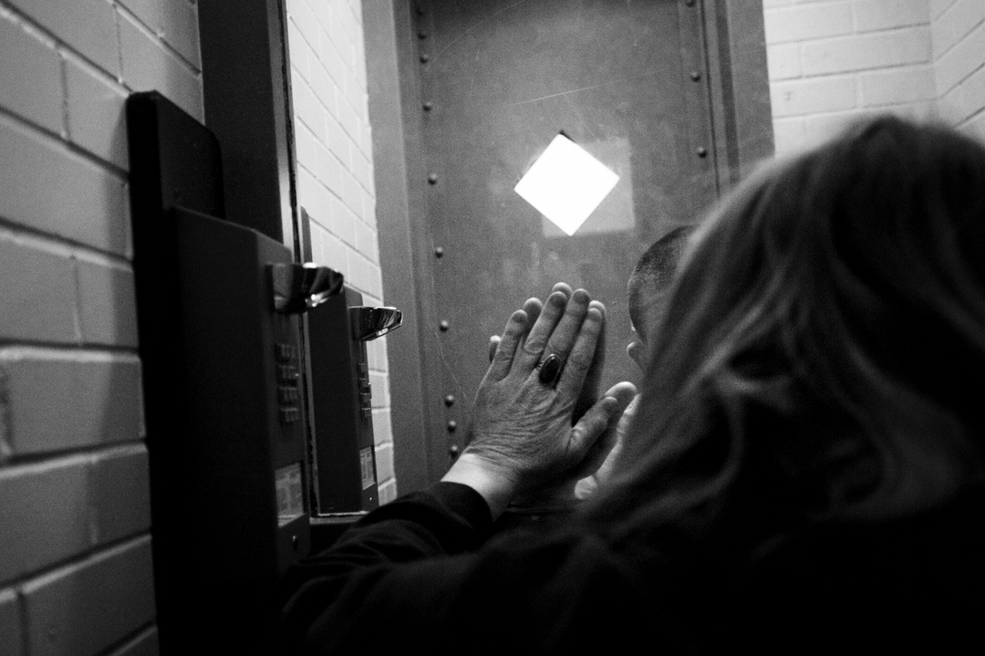  Gail Hammett holds her hand up to the glass in the Jackson County Jail on W. Wesley Street to match her son, James, who also raised his hand. Gail has been walking about two miles each way every Thursday since August to spend 15 minutes in county lo