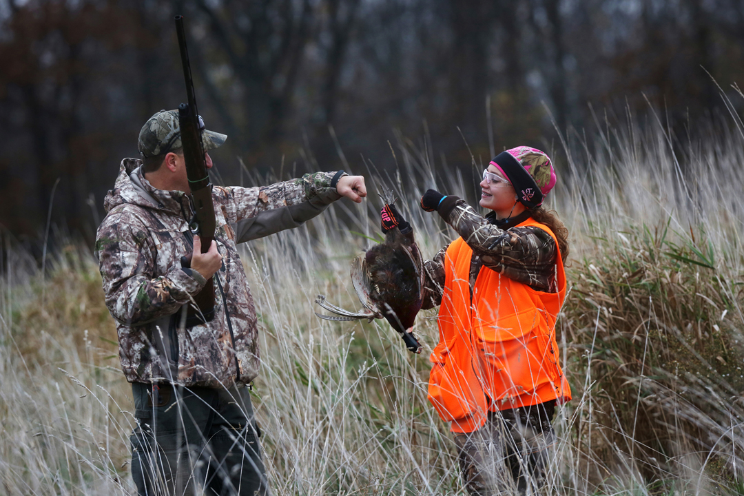  Nick Scholl, of Deerfield, left, congratulates his daughter Megan, 15, right, on bringing down her first pheasant while hunting Saturday, October 31, 2015, on land near Clinton, Mich. Megan and her sister Erika,18, were pheasant hunting for the firs